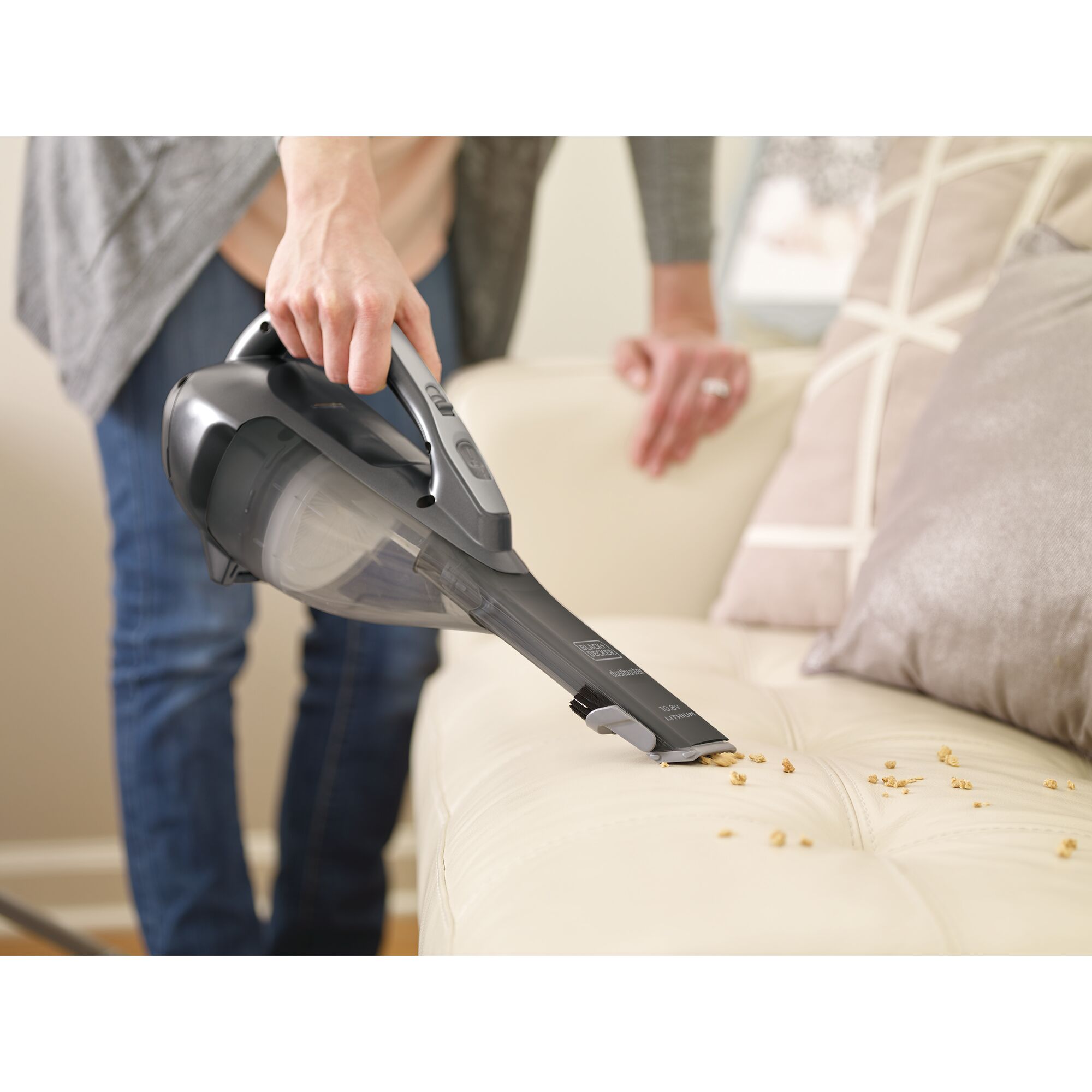 BLACKDECKER DVA320BF handheld vacuum cleaning beige sofa, crumbs visible, product photography.