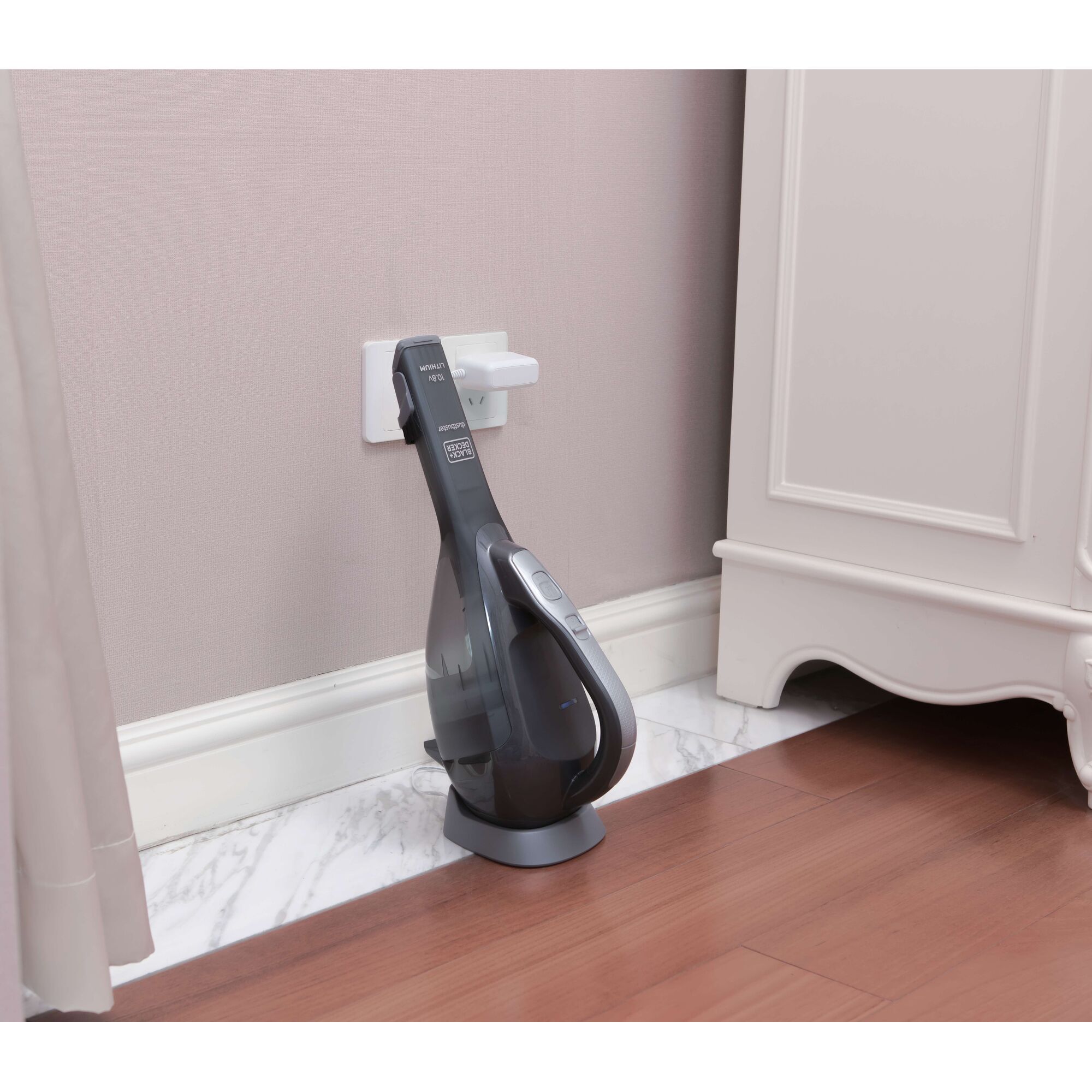 BLACKDECKER DVA320BF handheld vacuum cleaner on charging dock, side view, against wall in home.