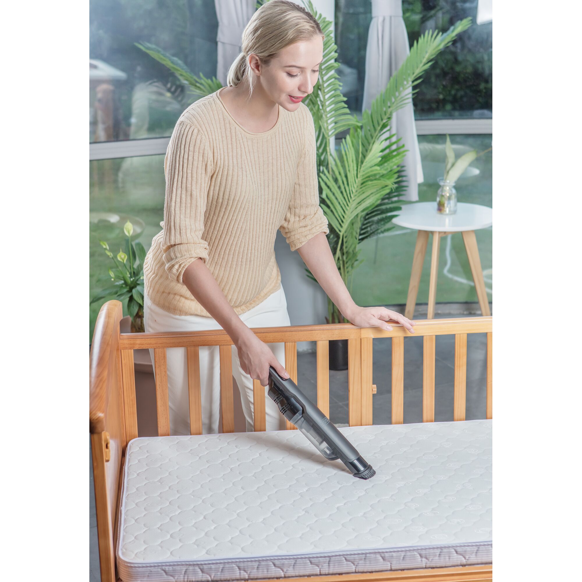 BLACKDECKER DVC320B01 handheld vacuum cleaning a crib mattress indoors.