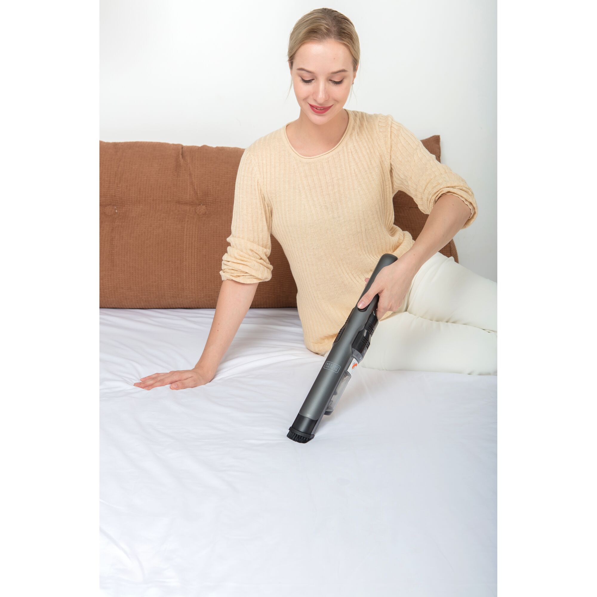 BLACKDECKER DVC320B01 handheld vacuum cleaner being used on a white sheet, front angle.