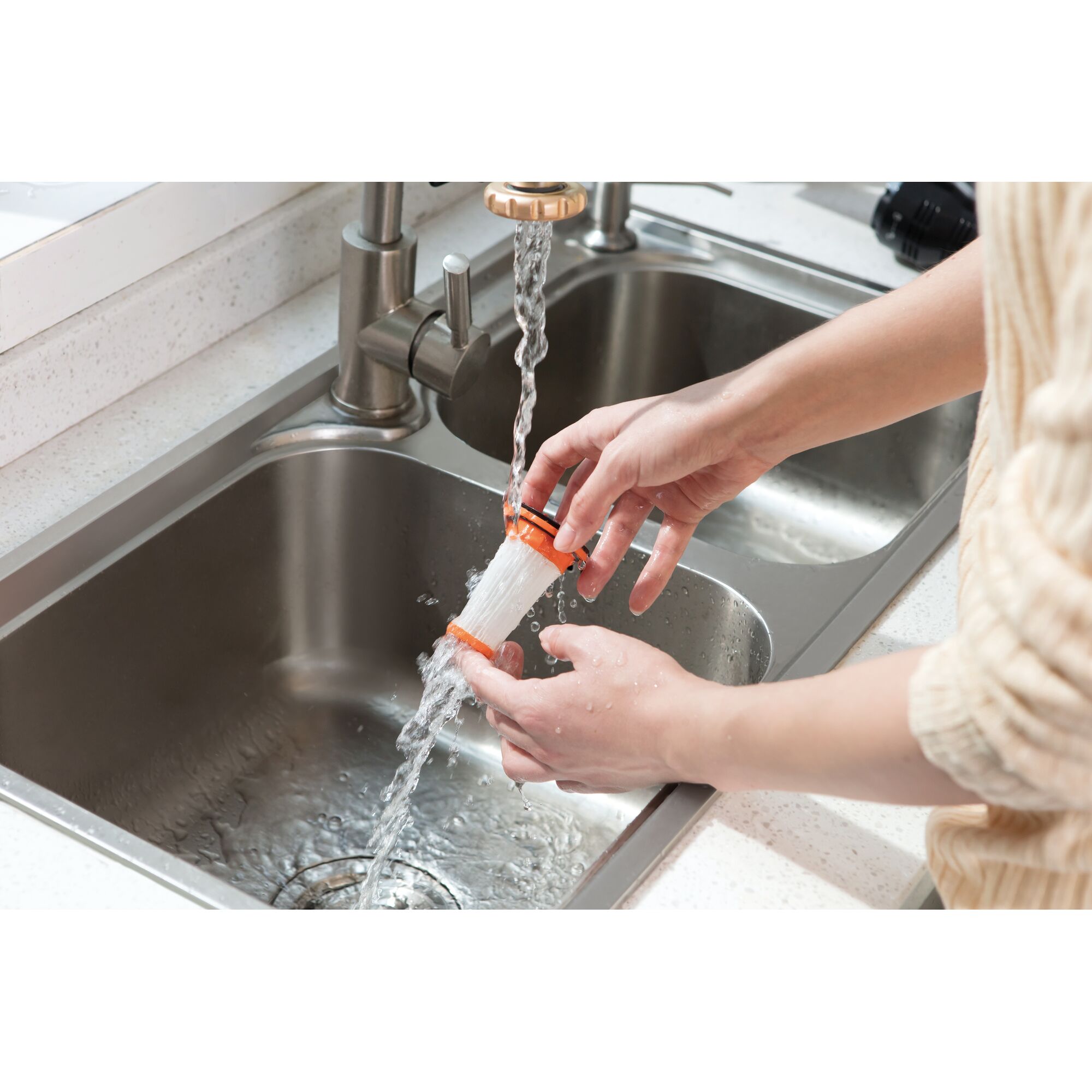 BLACKDECKER DVC320B01 filter being cleaned under running water in a kitchen sink, photography close-up.