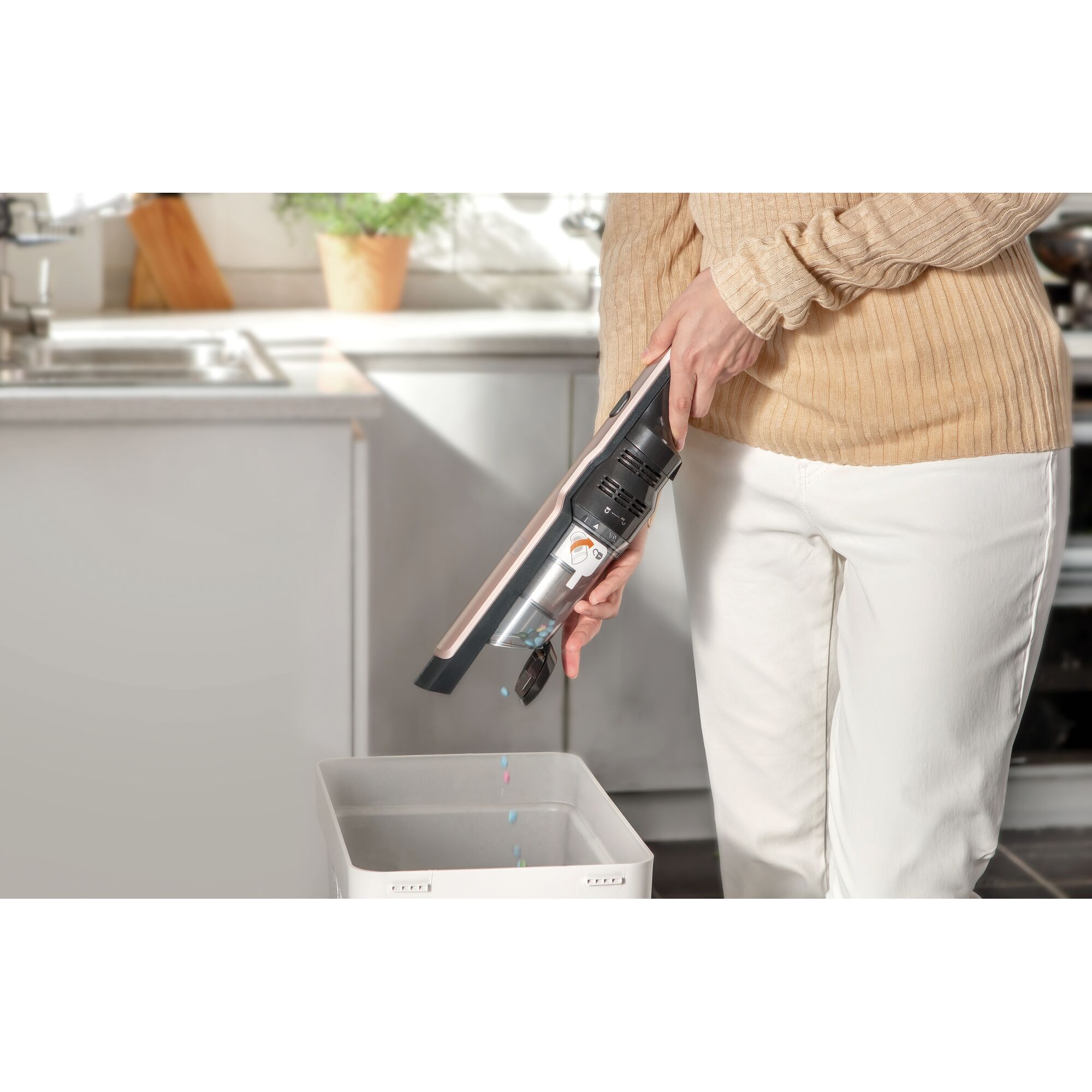 BLACKDECKER DVC320B24 handheld vacuum cleaner in use, emptied into a bin in a kitchen setting.