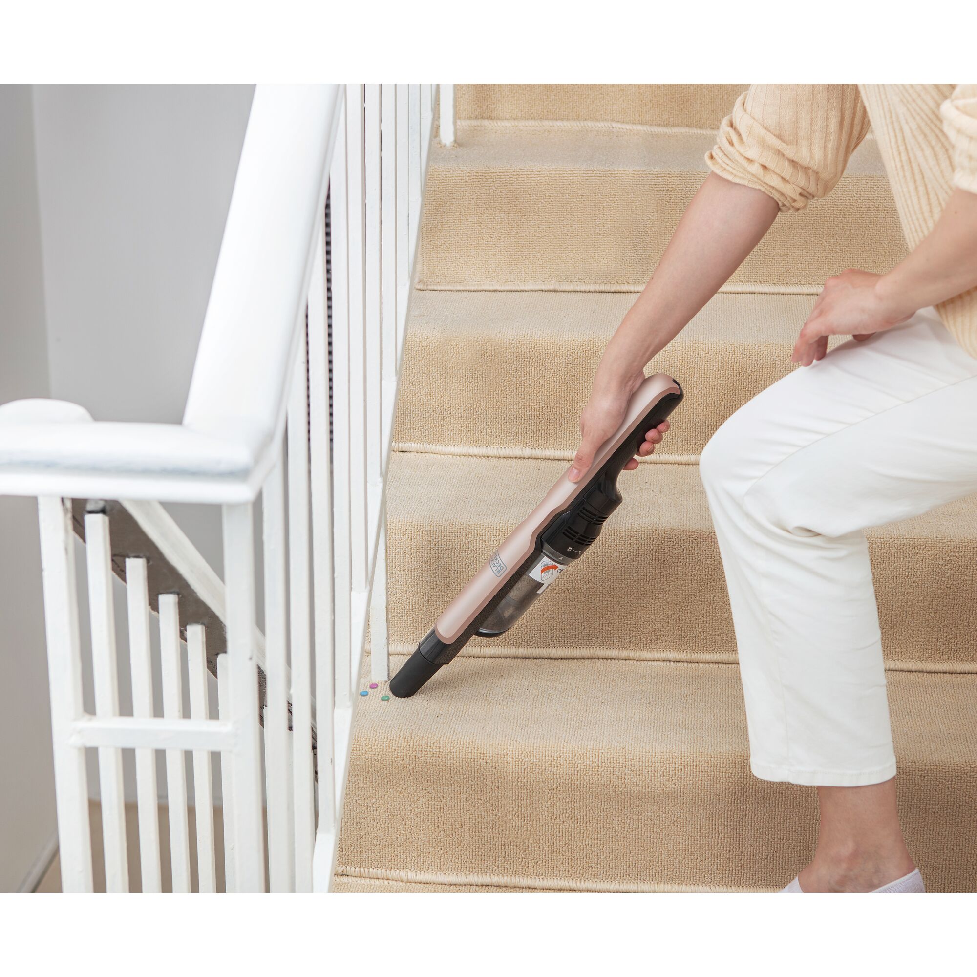 BLACKDECKER DVC320B24 handheld vacuum cleaning beige carpeted stairs, side view.
