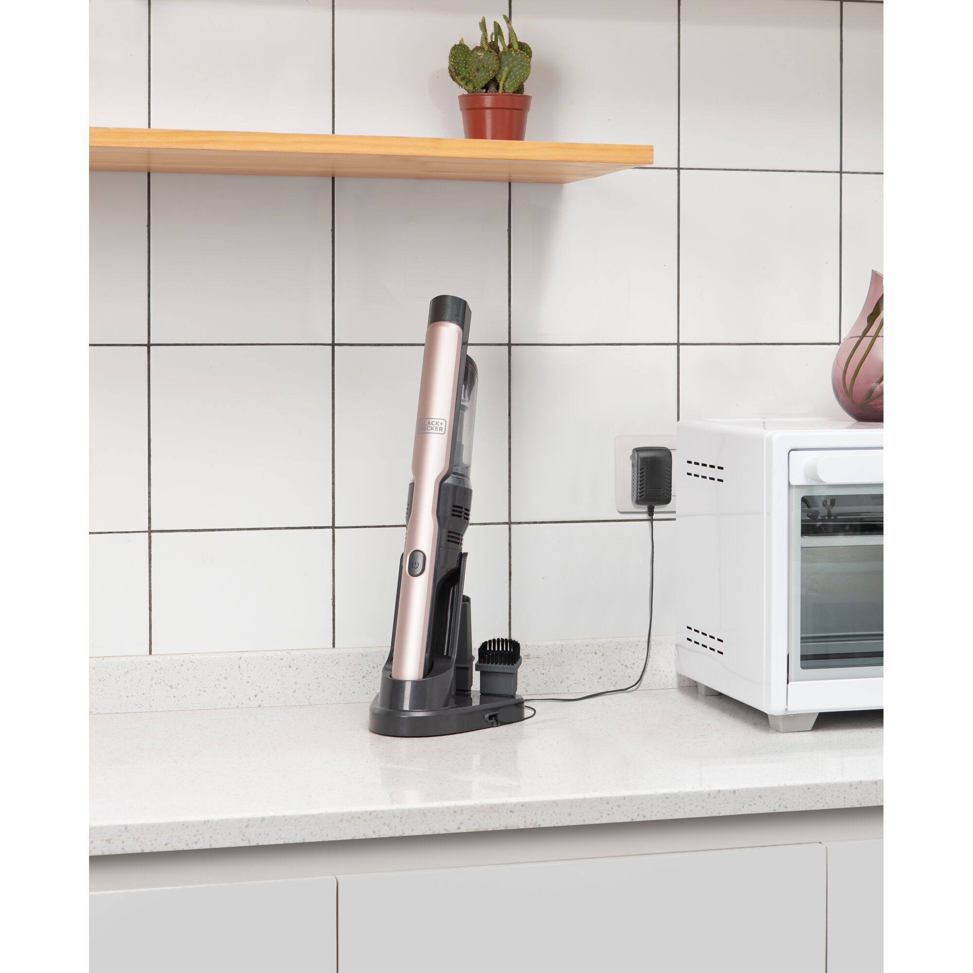 BLACKDECKER DVC320B24 handheld vacuum on charging base on a kitchen counter near a white oven.