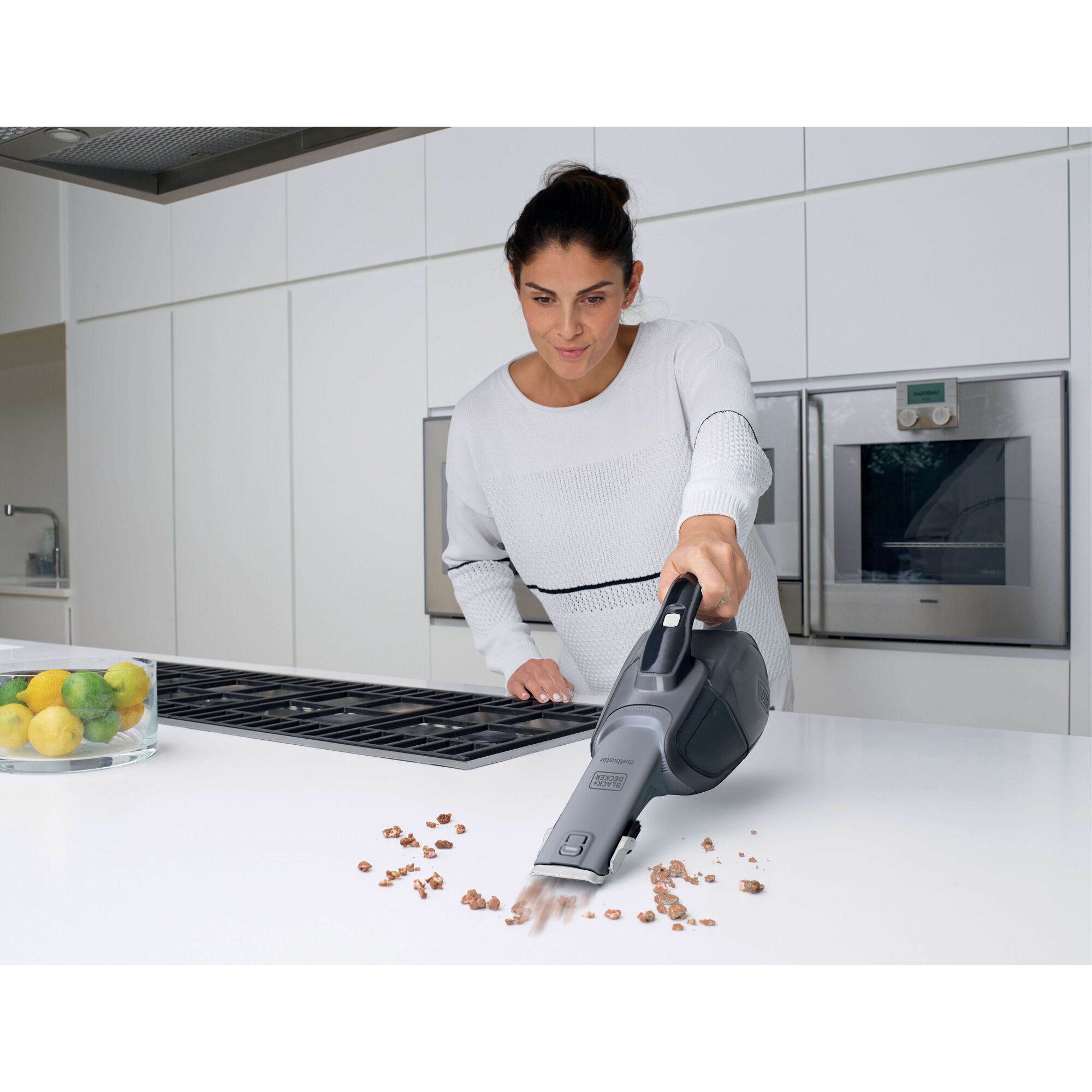 BLACKDECKER DVJ215B handheld vacuum cleaning crumbs on white kitchen counter.