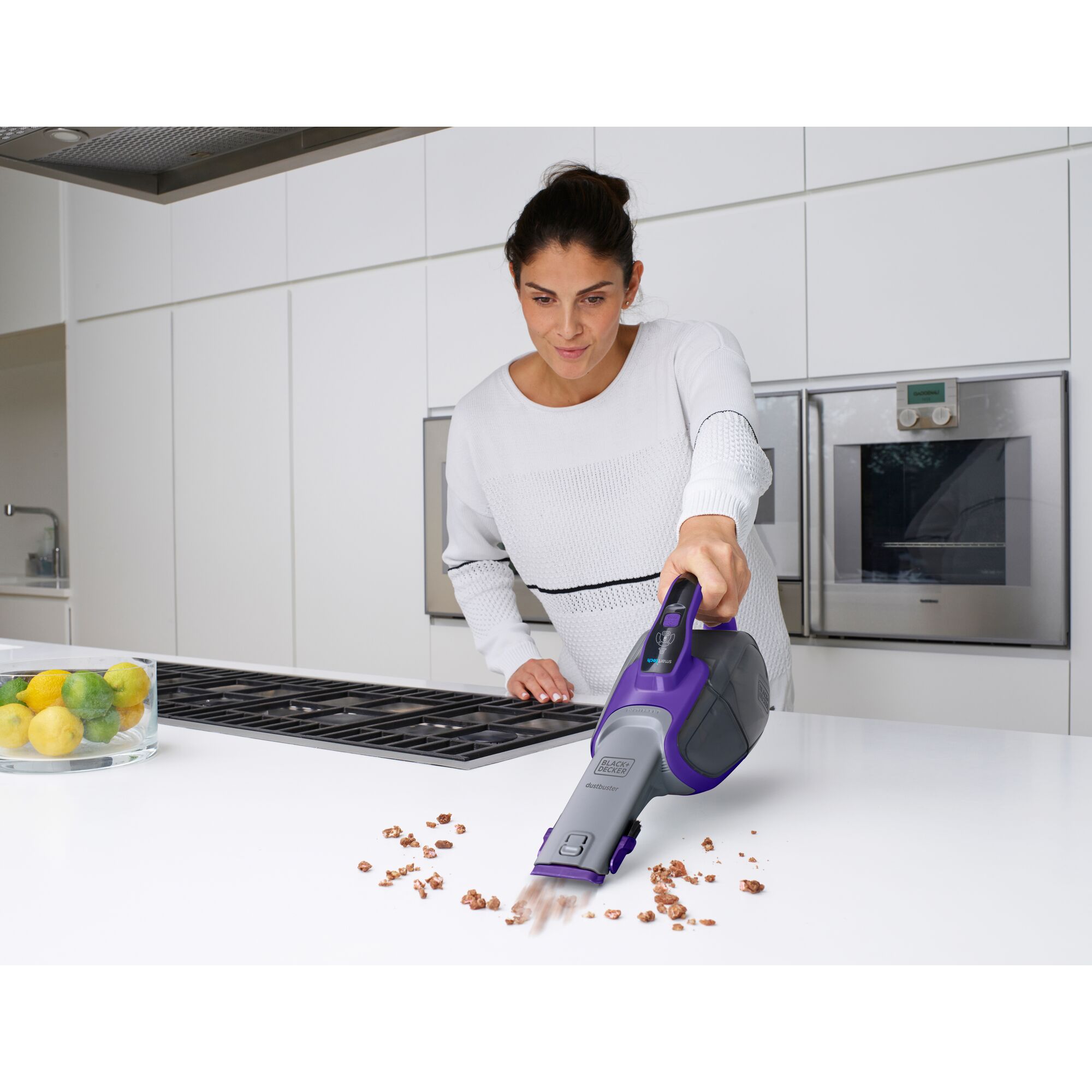 BLACKDECKER DVJ325BFSP handheld vacuum cleaning crumbs on kitchen counter, purple and gray design.