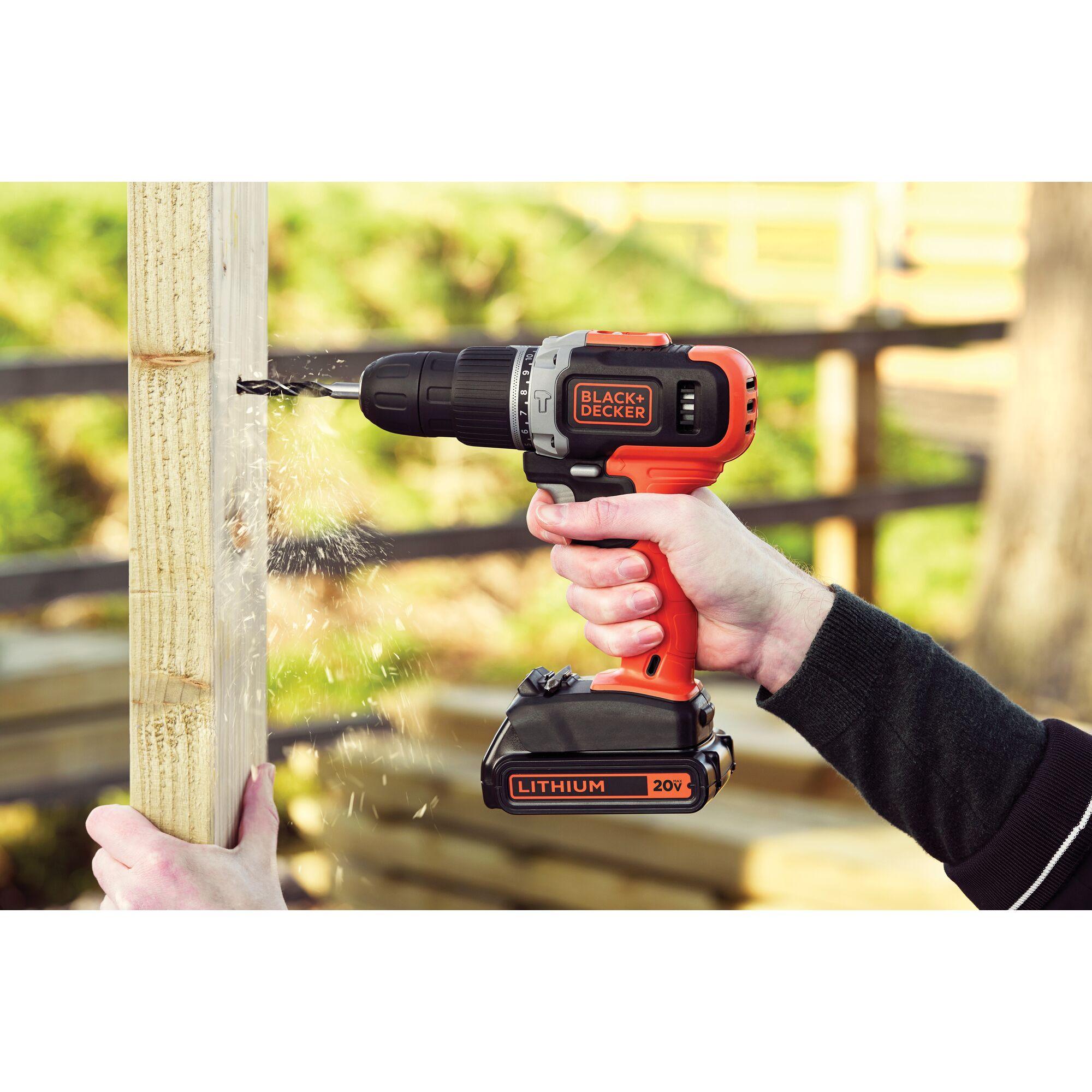 BLACK+DECKER EBCD703K cordless drill in use, drilling into wood, visible sparks, outdoors, 20V lithium battery.