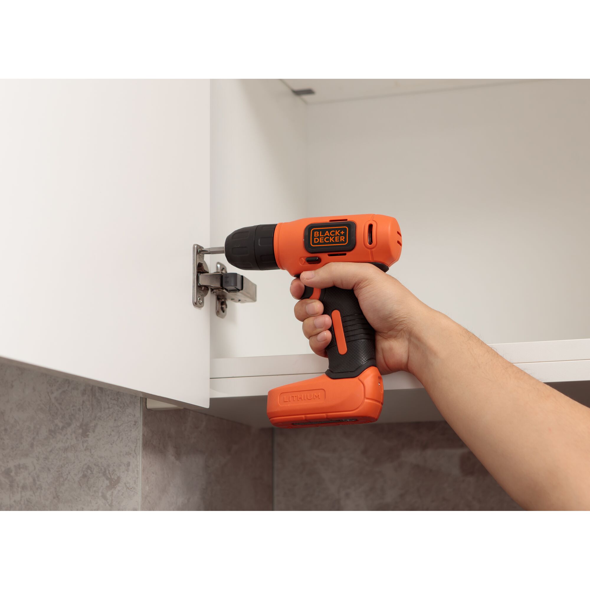 BLACKDECKER EBDCD8HDPK cordless drill used to tighten a cabinet hinge in a kitchen setting.