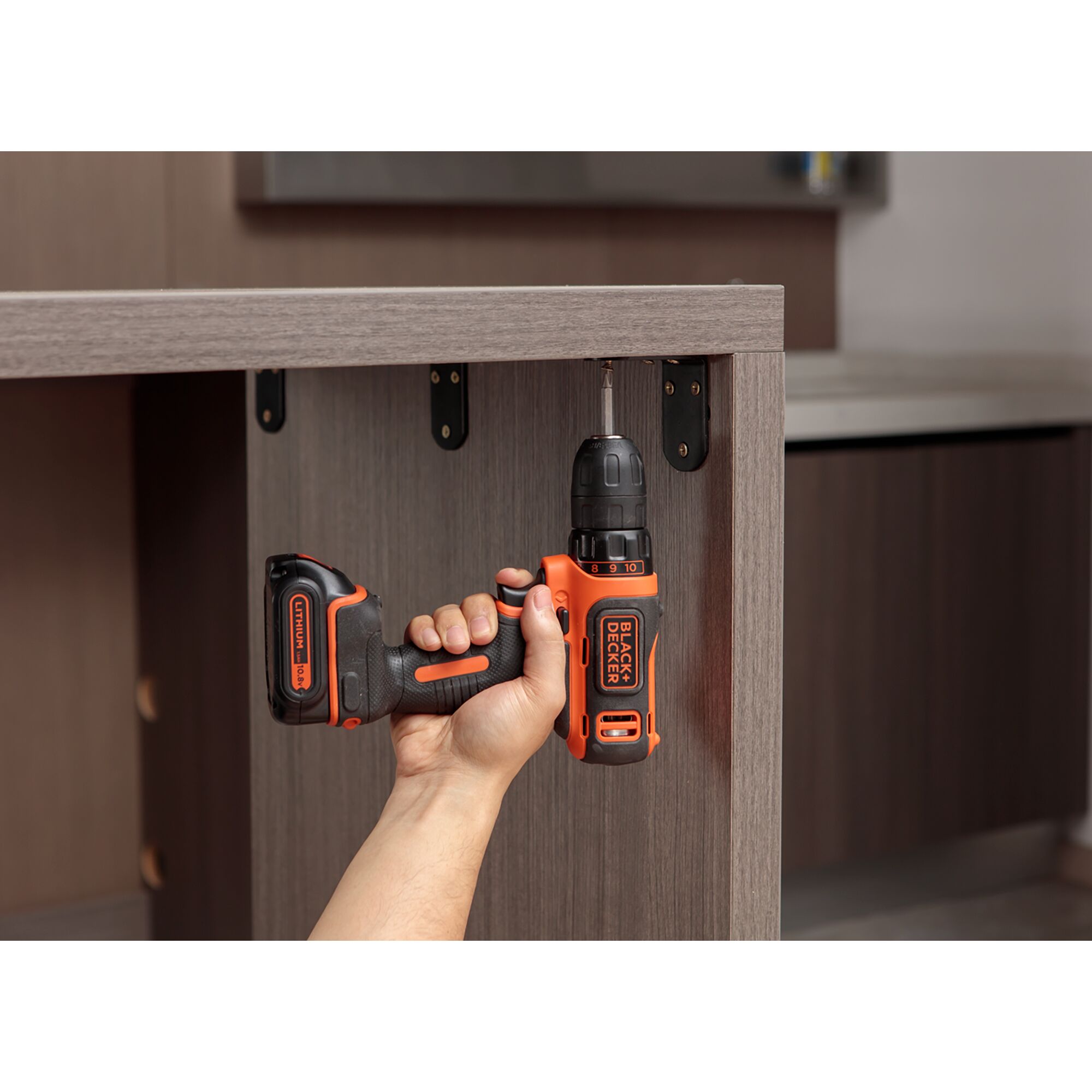 BLACK+DECKER EBDCDD12HS cordless drill being used to screw into a cabinet, close-up side view.