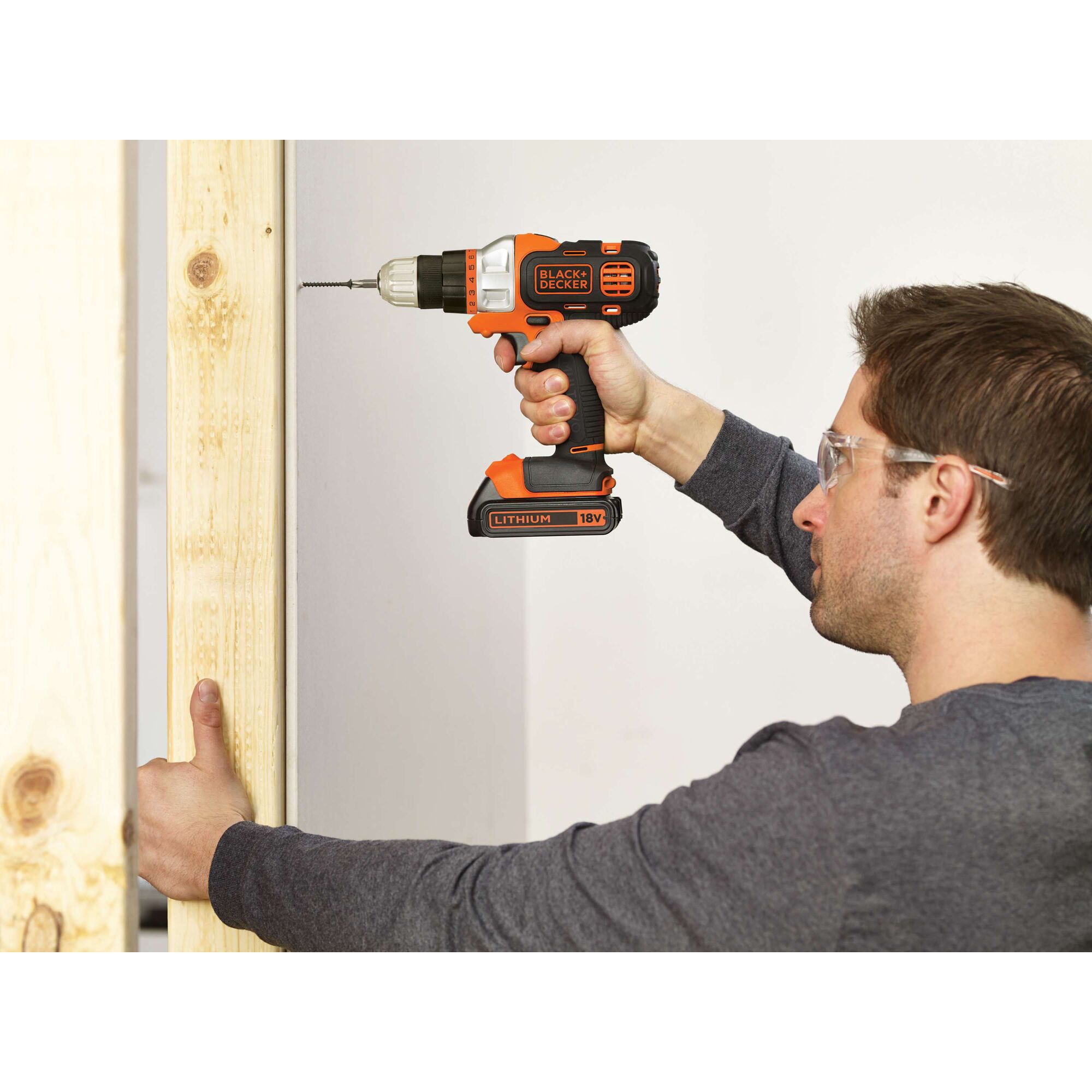 Photo of BLACKDECKER EDD183 18V cordless drill in use, orange and black, drilling into wooden beam.
