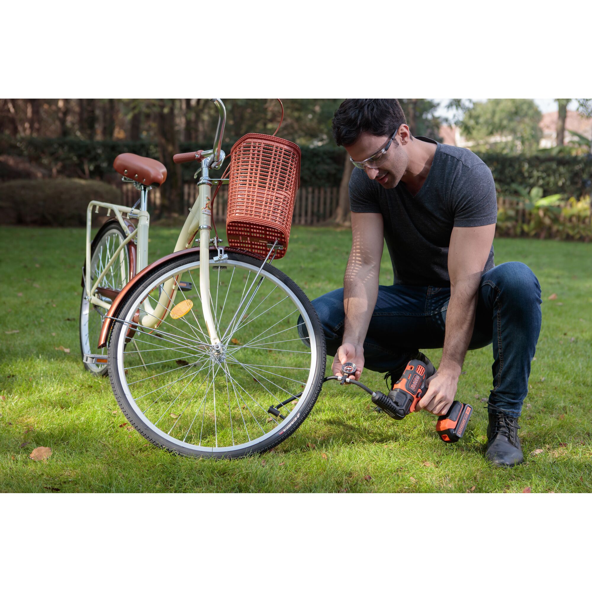 BLACKDECKER EIF183 cordless drill used to repair bicycle outdoors, orange and black tool, grass background.