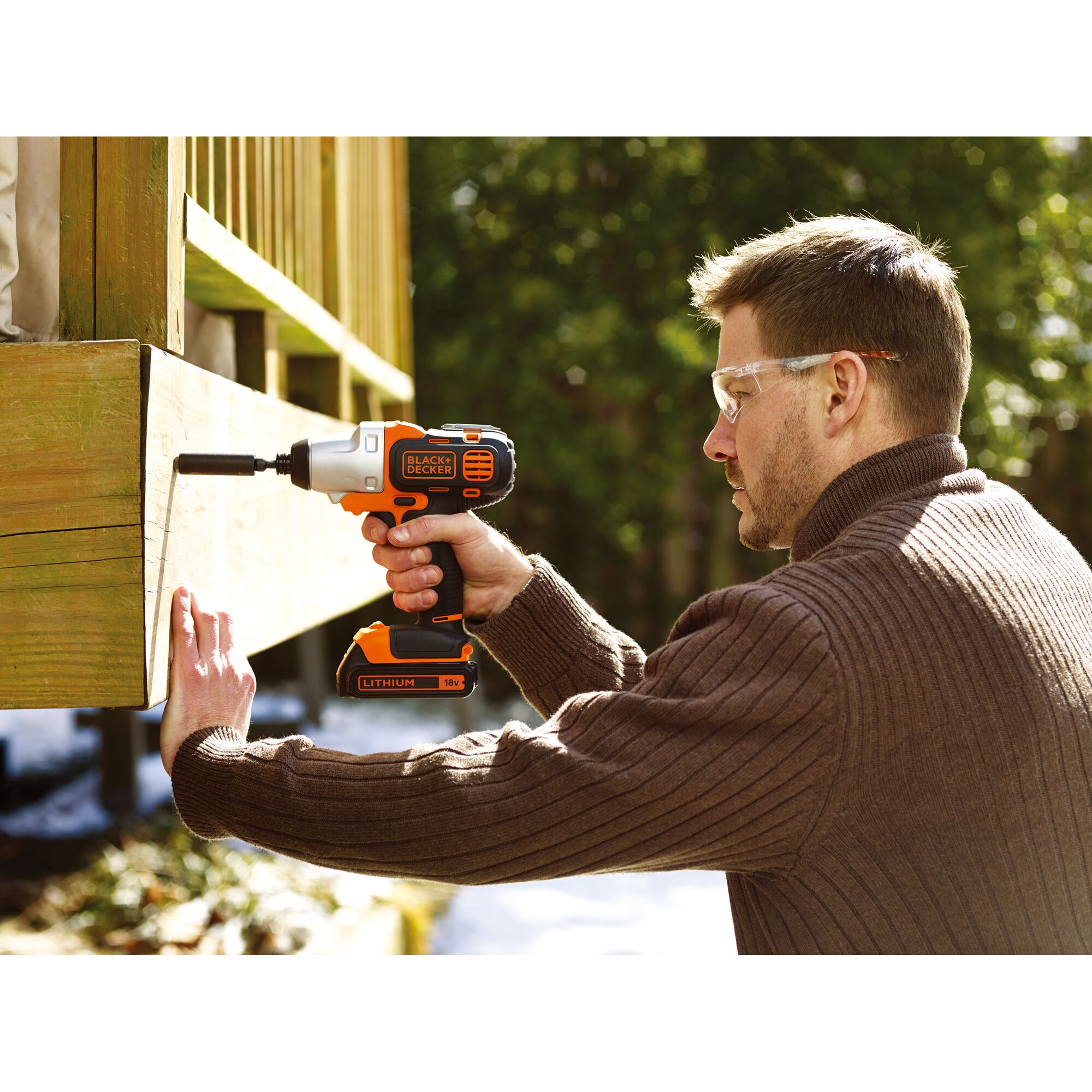 BLACKDECKER EIH183 cordless impact driver in use outdoors, orange and black, woodworking project.