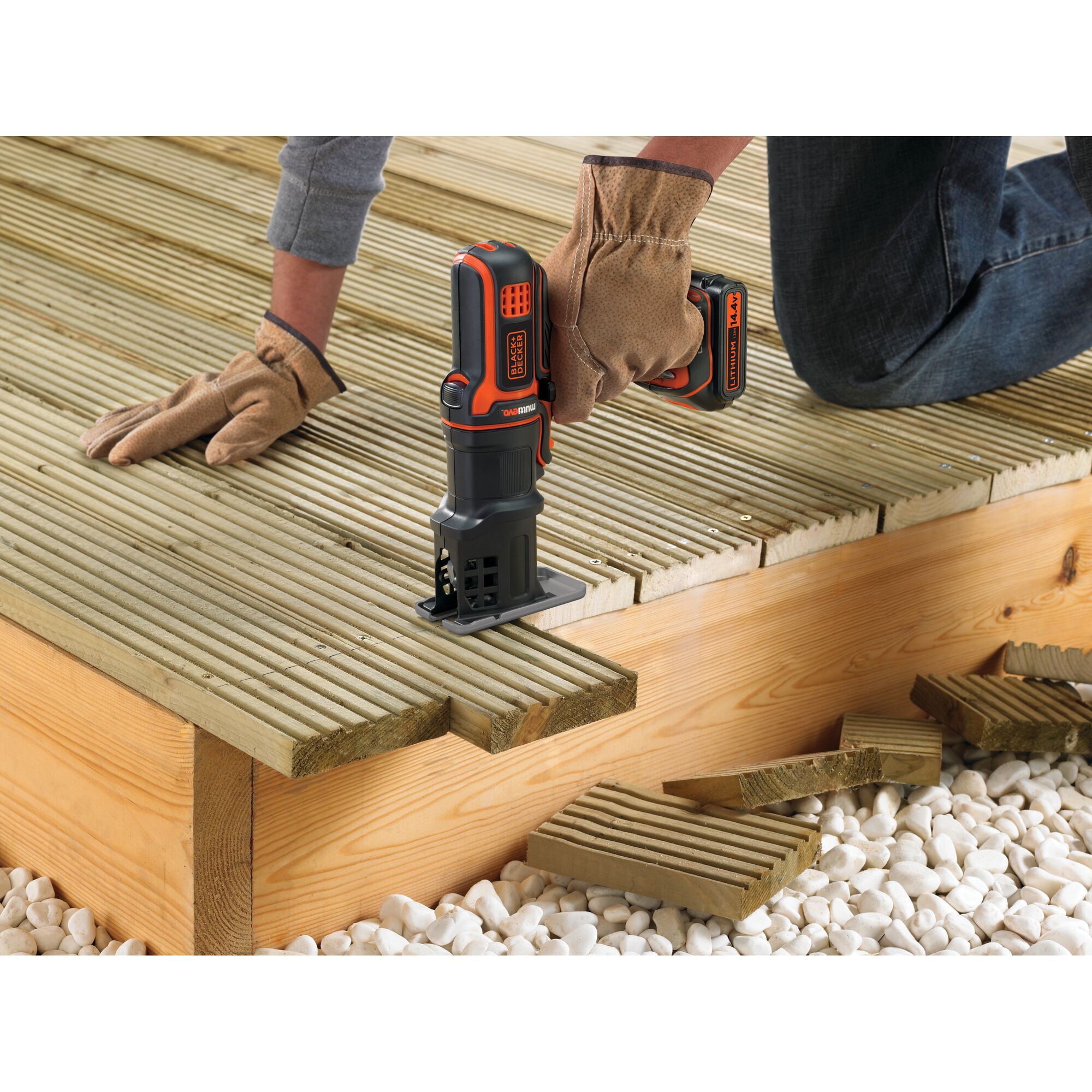 BLACKDECKER EJS183 jigsaw used to cut wooden deck planks, close-up of hands in gloves, outdoor setting.