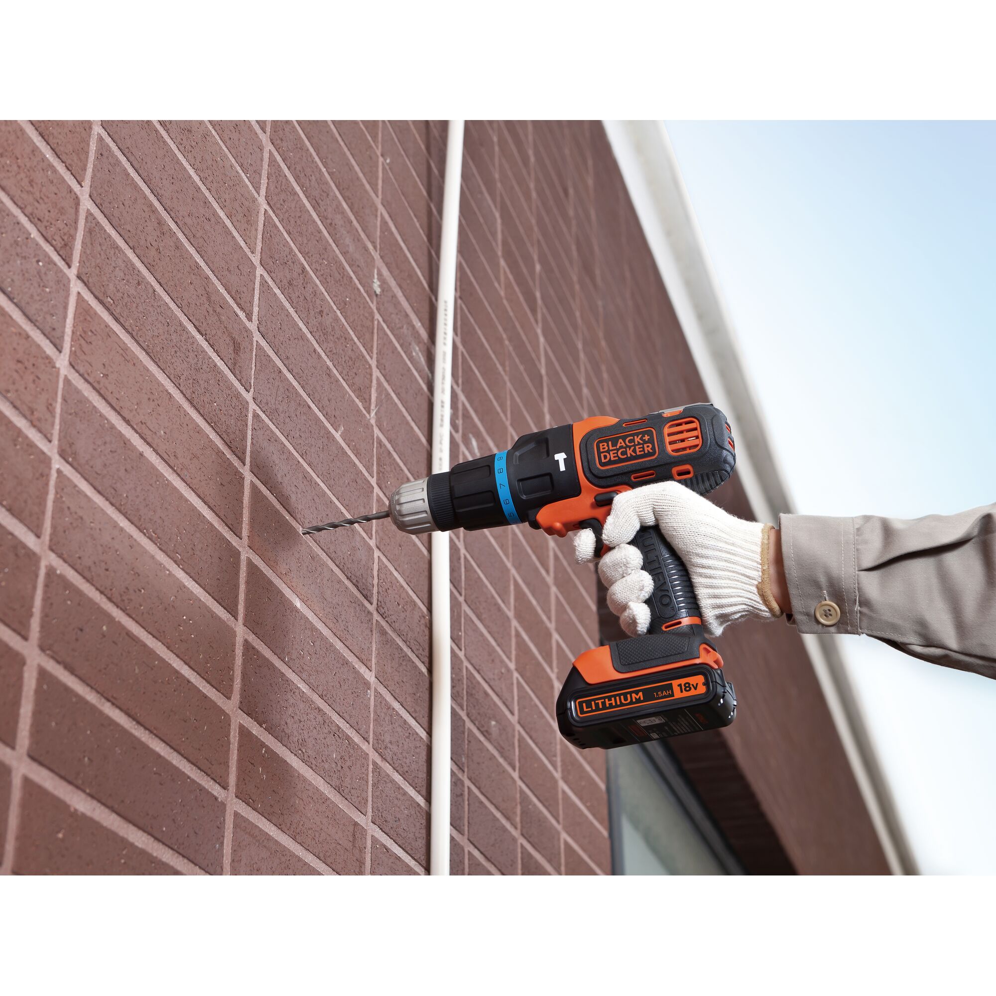 BLACK+DECKER EVO184K cordless drill, 18V, in use drilling a brick wall, side view.