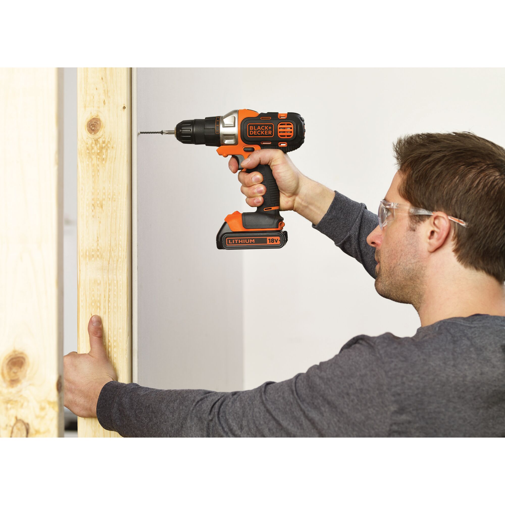 BLACKDECKER EVO184K cordless drill in use on wooden beam, orange and black, 18V lithium battery.