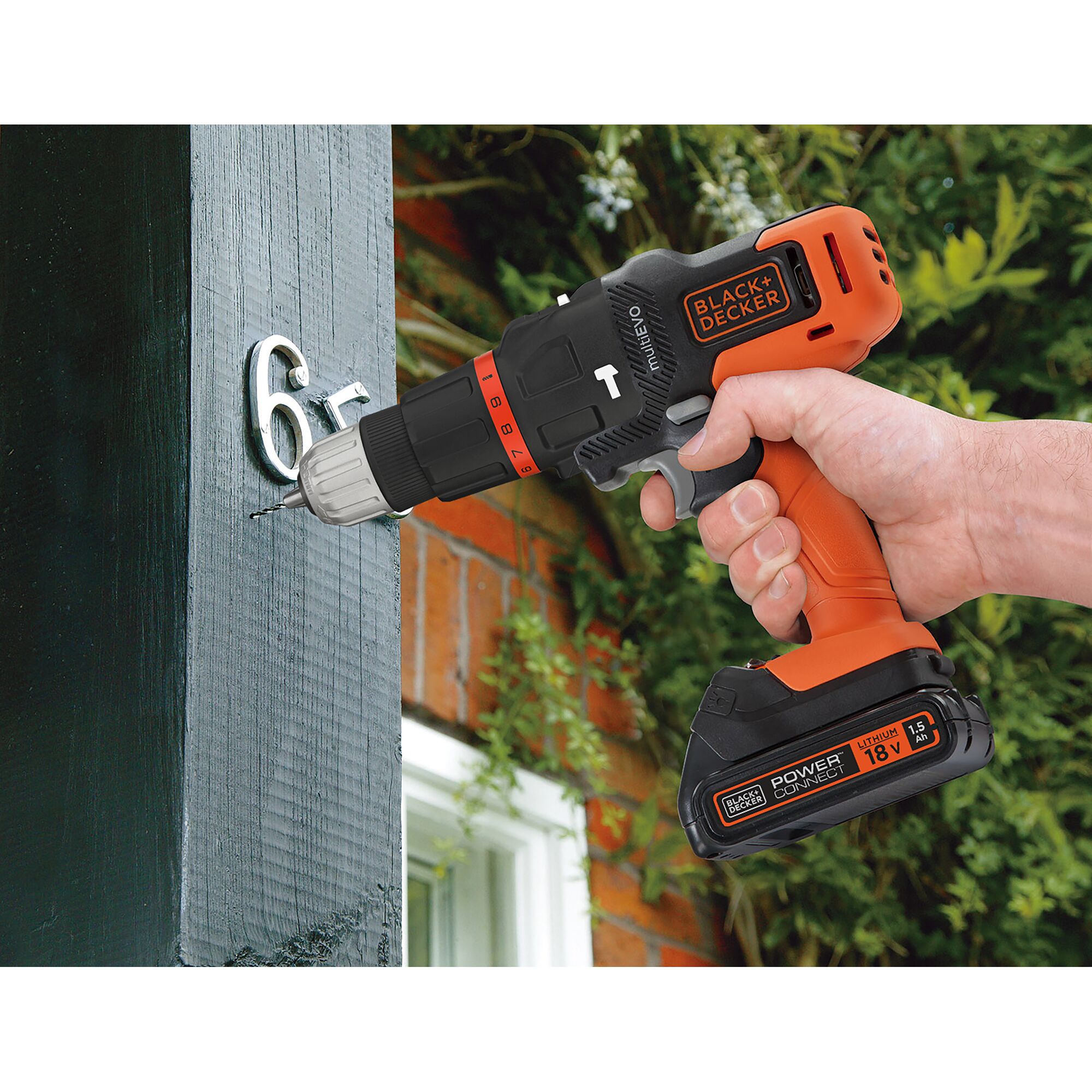 BLACKDECKER EVO185B1 cordless drill being used to attach metal numbers to a wooden post outdoors.