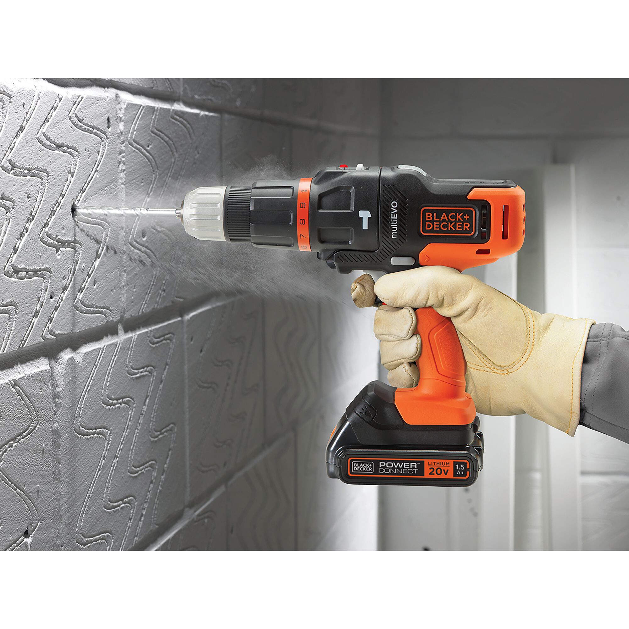 Photo of BLACK+DECKER EVO185B1 cordless drill in use on a textured wall, orange and black design, held by gloved hand.