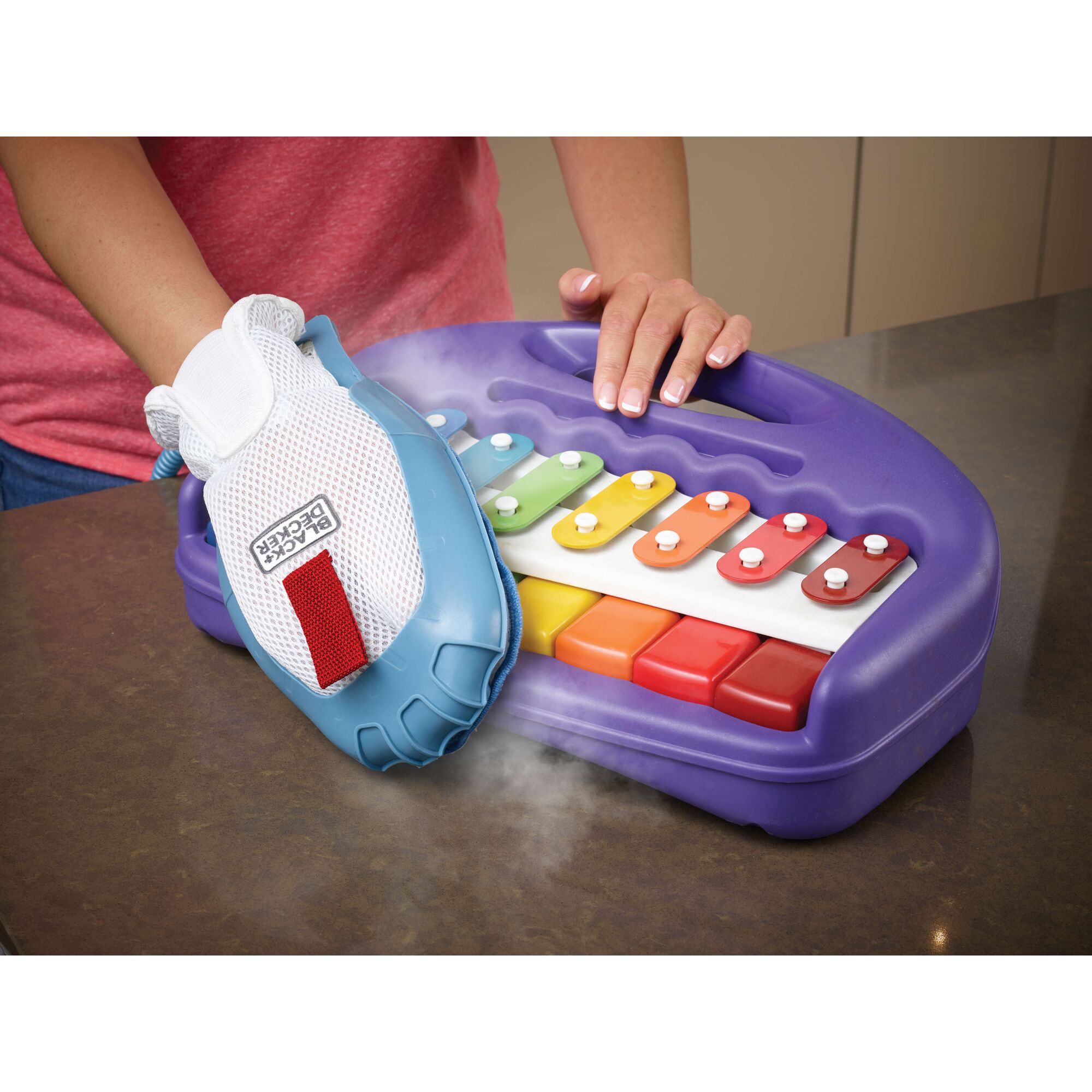 BLACKDECKER FSH10SM steam glove cleaning a purple toy xylophone with multicolored keys on countertop