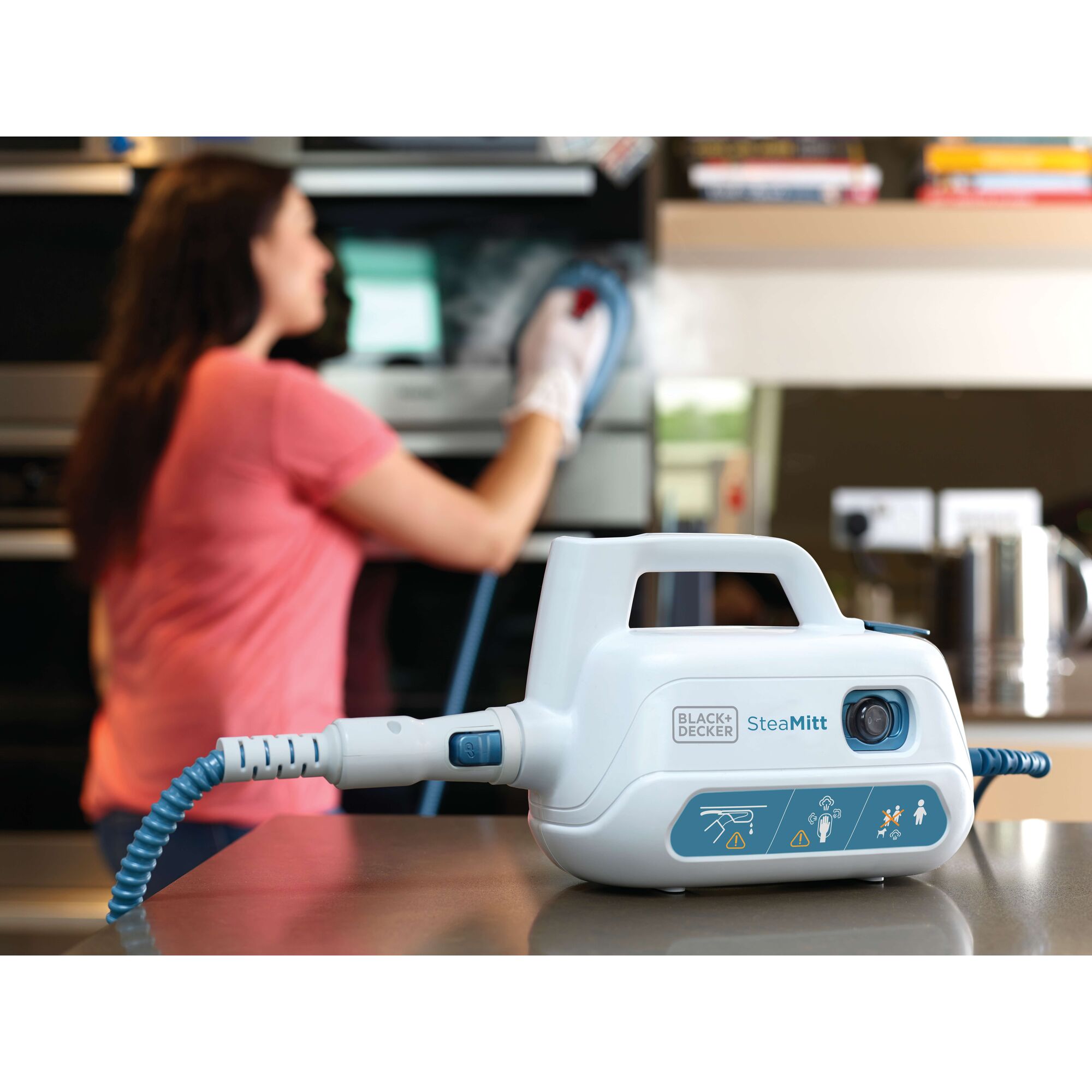 BLACKDECKER FSH10SM steam cleaning device on counter with person using it to clean kitchen appliance.
