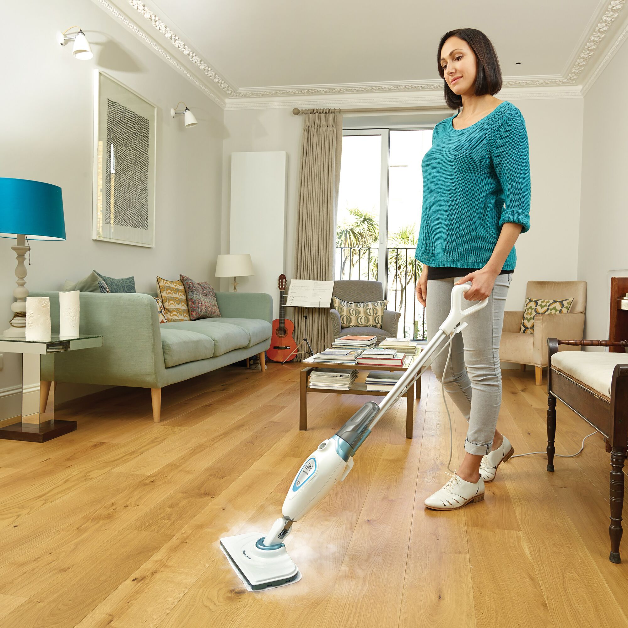 BLACK+DECKER FSM1605 steam mop cleaning wood floor in modern living room, photographed from the side.