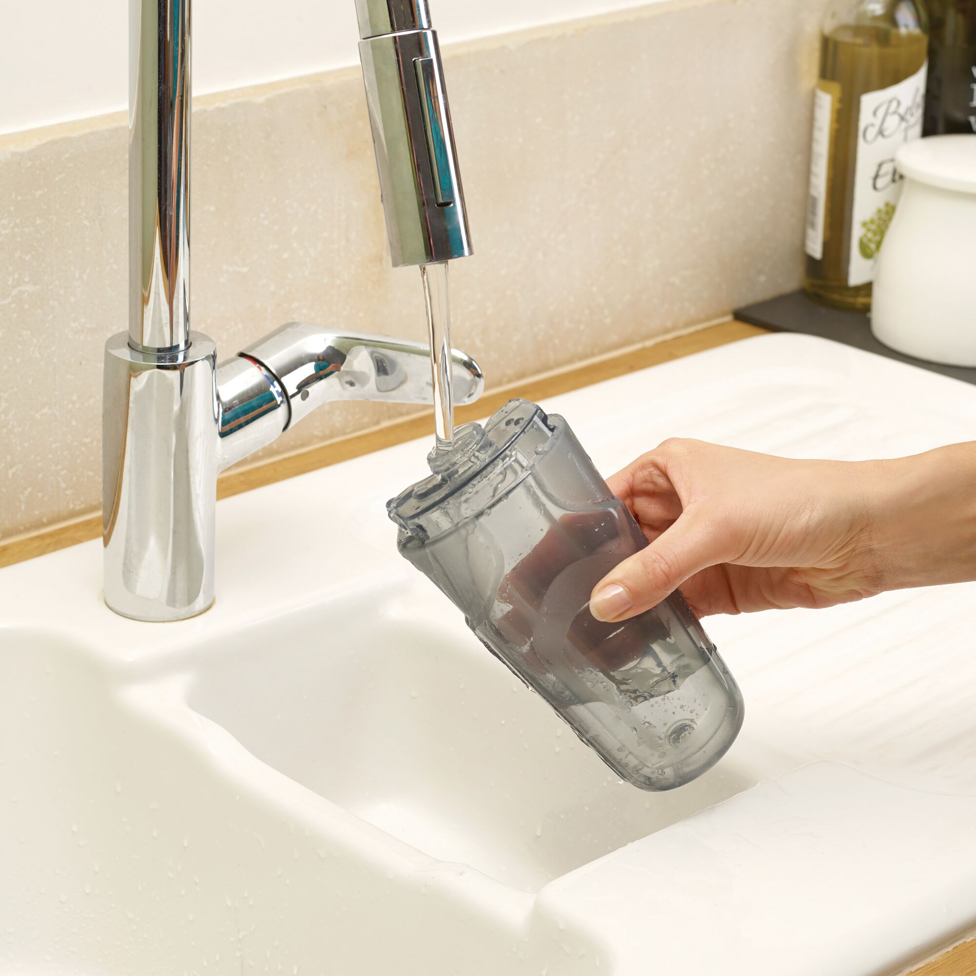 BLACKDECKER FSM1605 water tank being rinsed under a faucet in a kitchen sink, close-up.