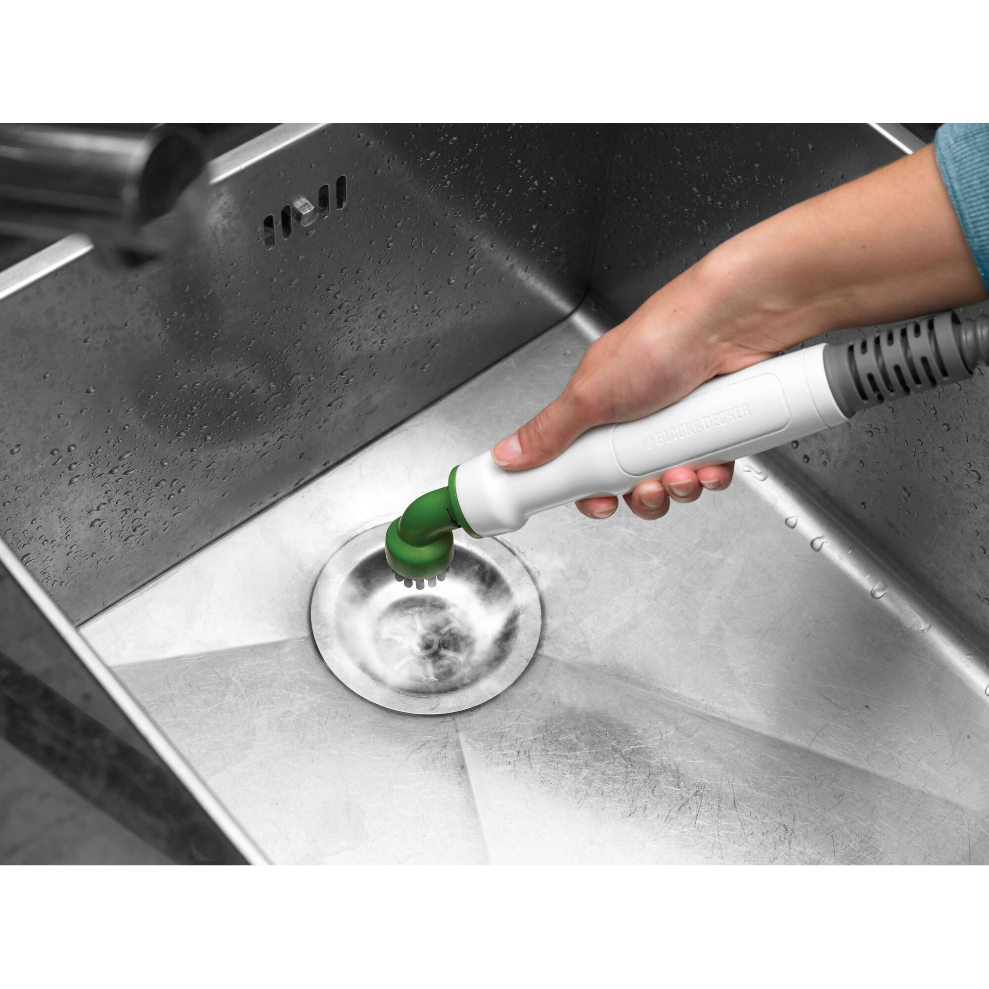 BLACKDECKER FSMH1300FX handheld steam cleaner with green brush attachment cleaning a stainless steel sink.