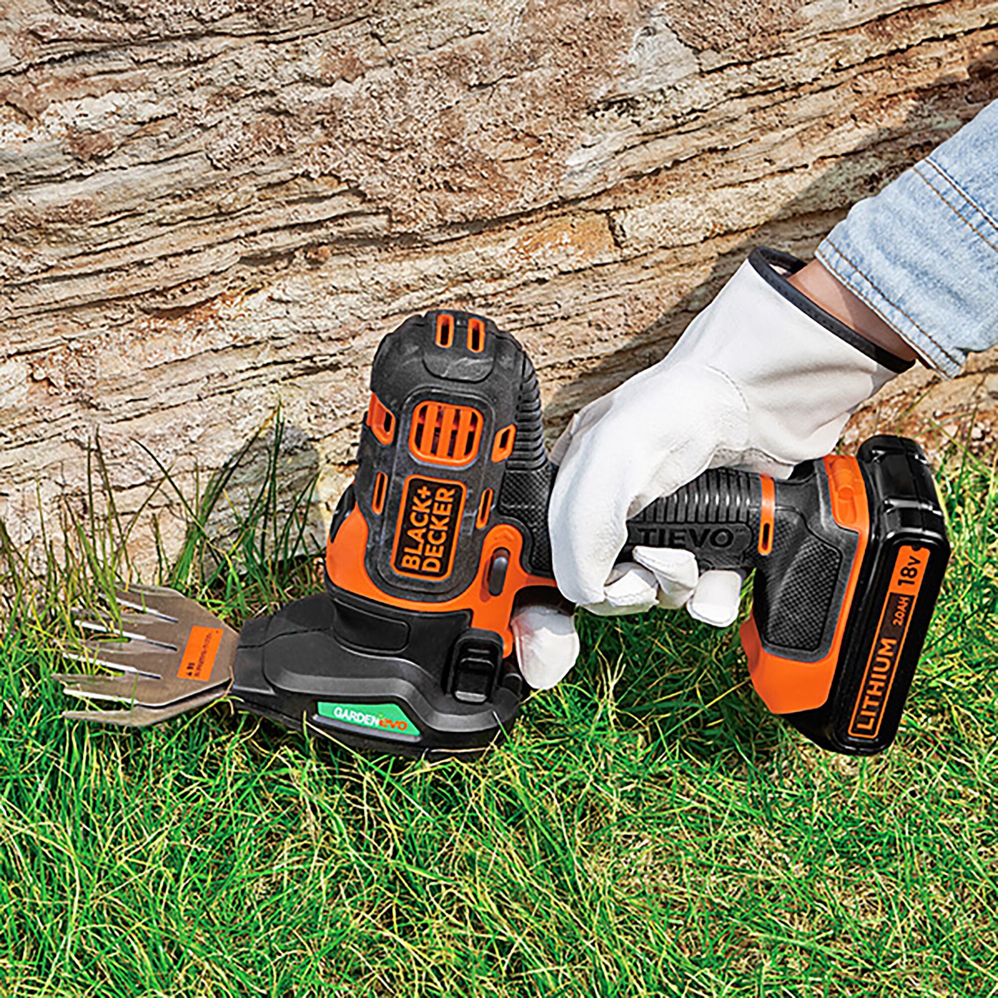 BLACKDECKER GEVO183N handheld cordless grass shear used on lawn, orange and black, garden tool.