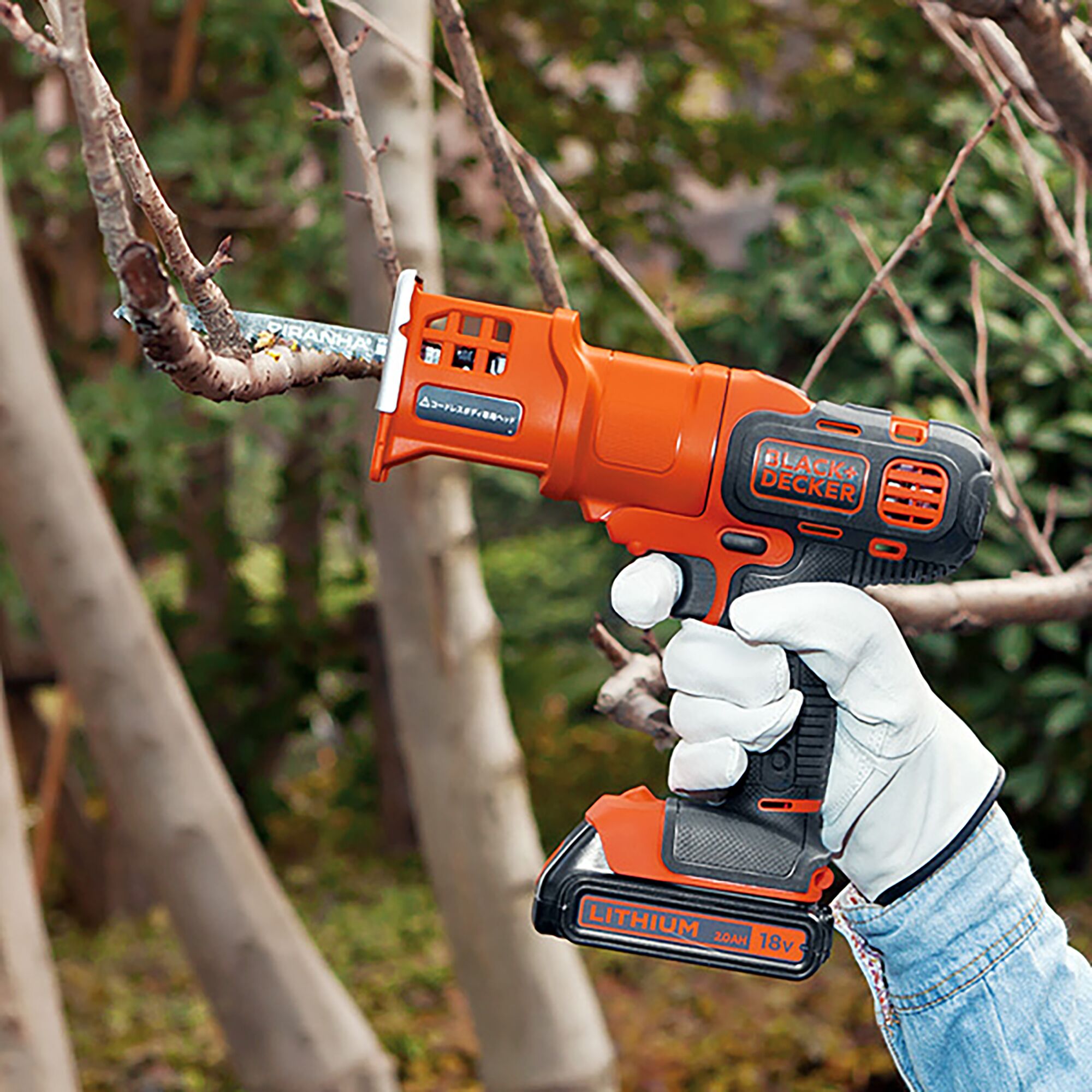 BLACKDECKER GEVO183N cordless reciprocating saw cutting tree branch outdoors, orange and black color.