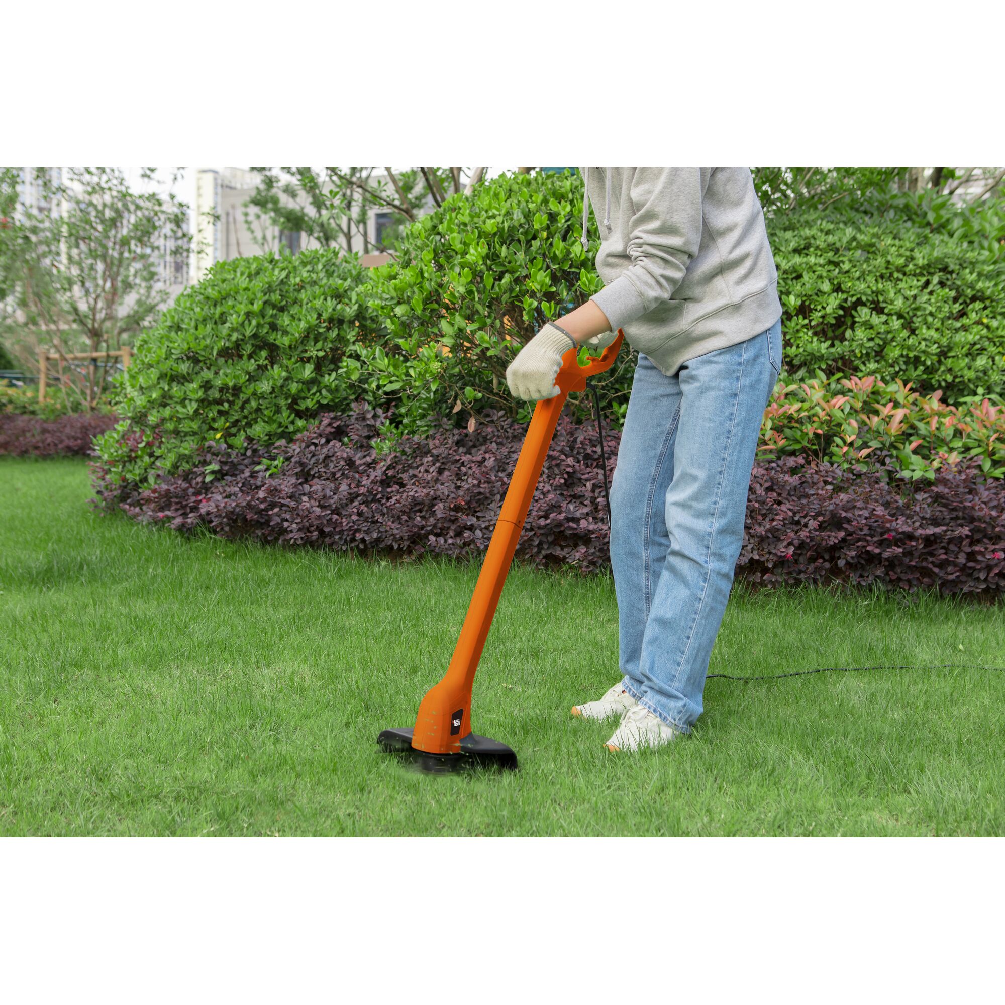 BLACKDECKER GL260 orange electric grass trimmer being used in a garden, lawn maintenance scene.
