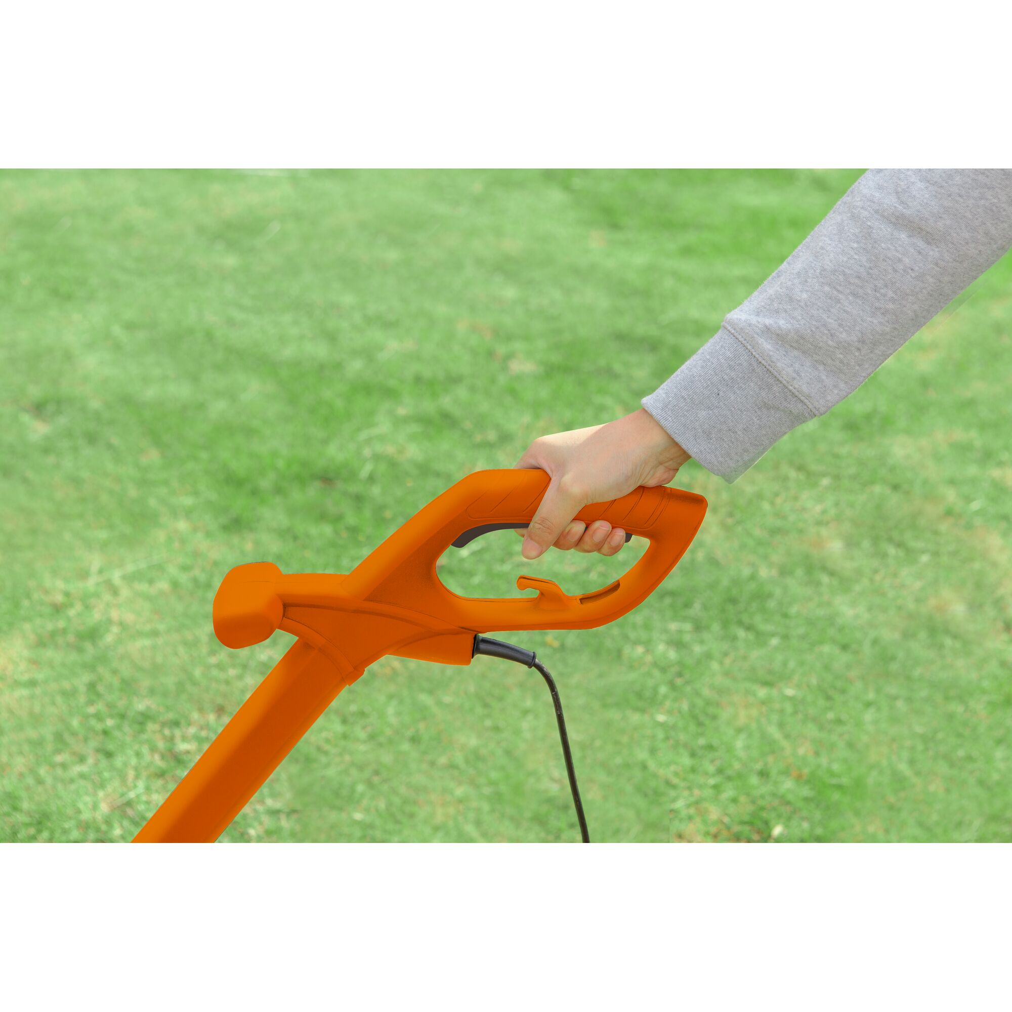 BLACKDECKER GL260 orange handle of grass trimmer held outdoors on lawn.