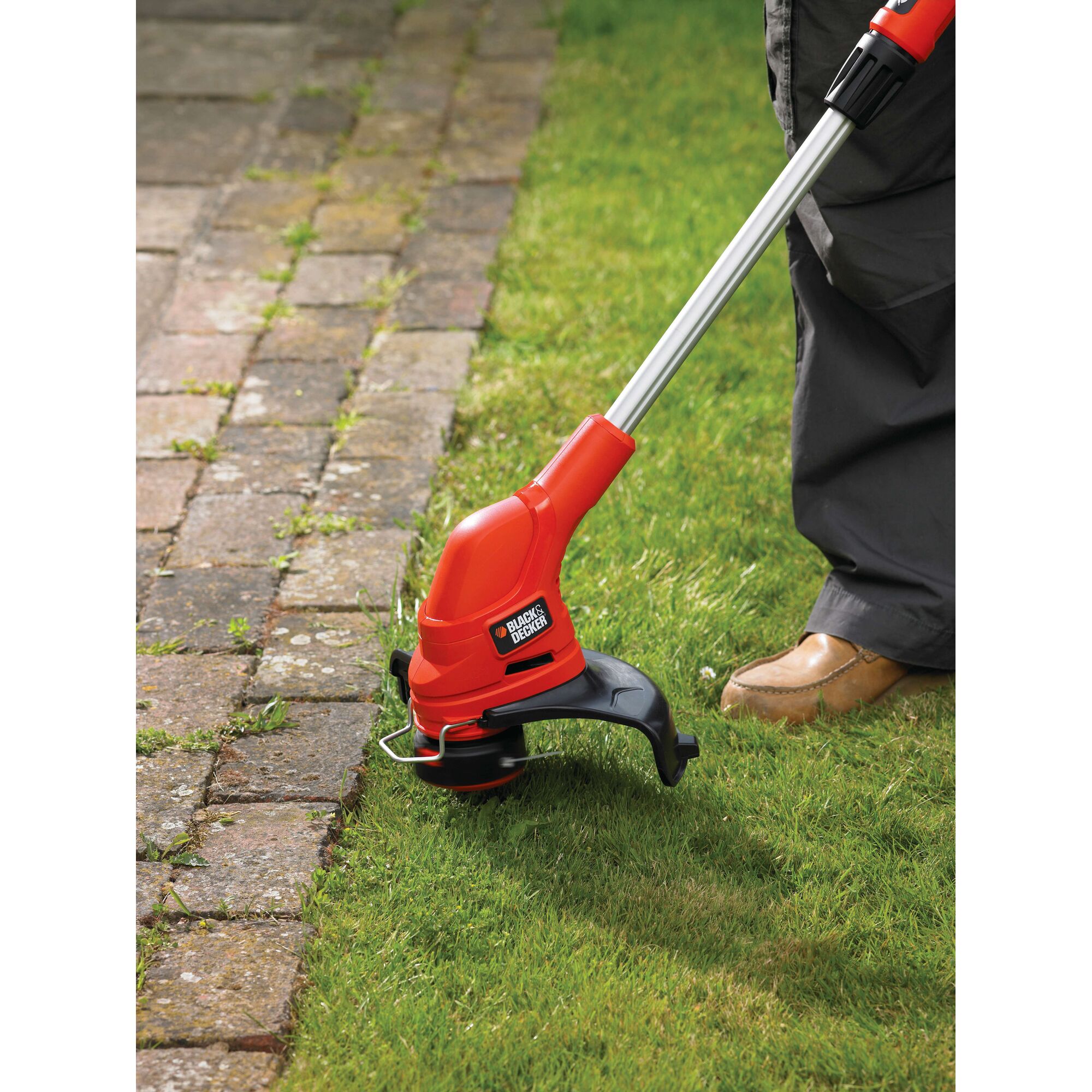 BLACKDECKER GL5530 grass trimmer in use trimming lawn edge beside stone path.