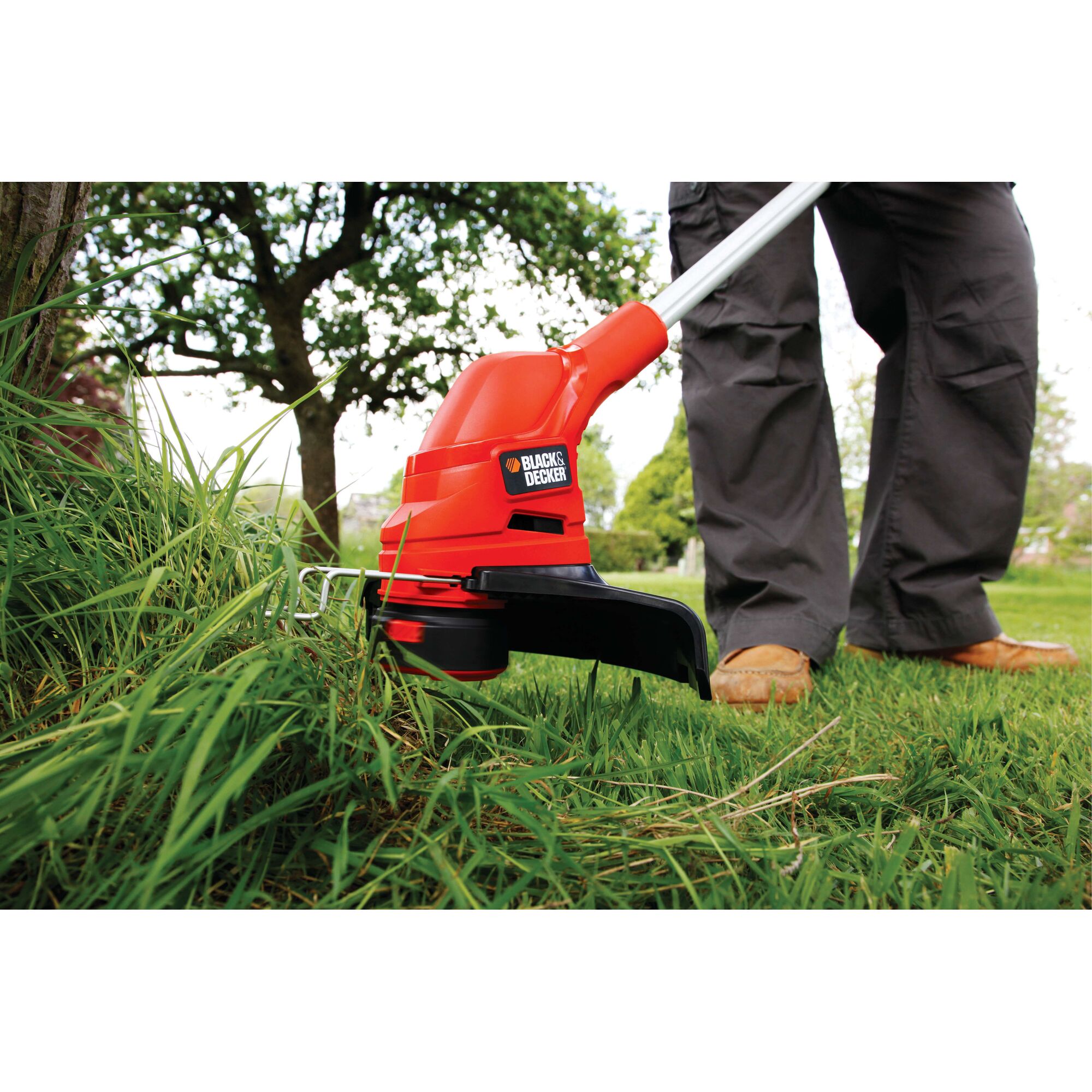 BLACKDECKER GL5530 grass trimmer in use outdoors, close-up showing red body and cutting head.