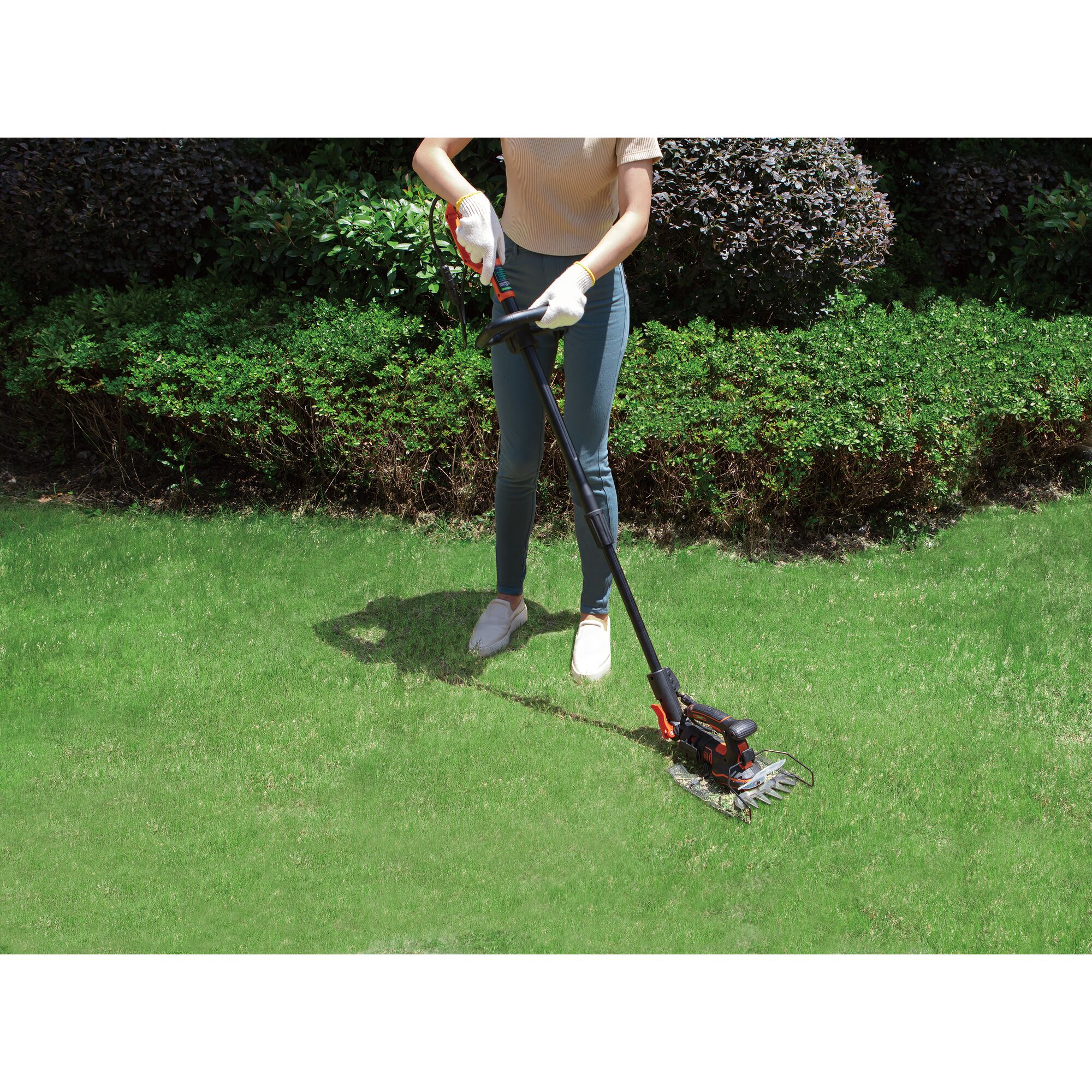 BLACKDECKER GPSH1820 cordless grass shear used on green lawn with shrubs in background.