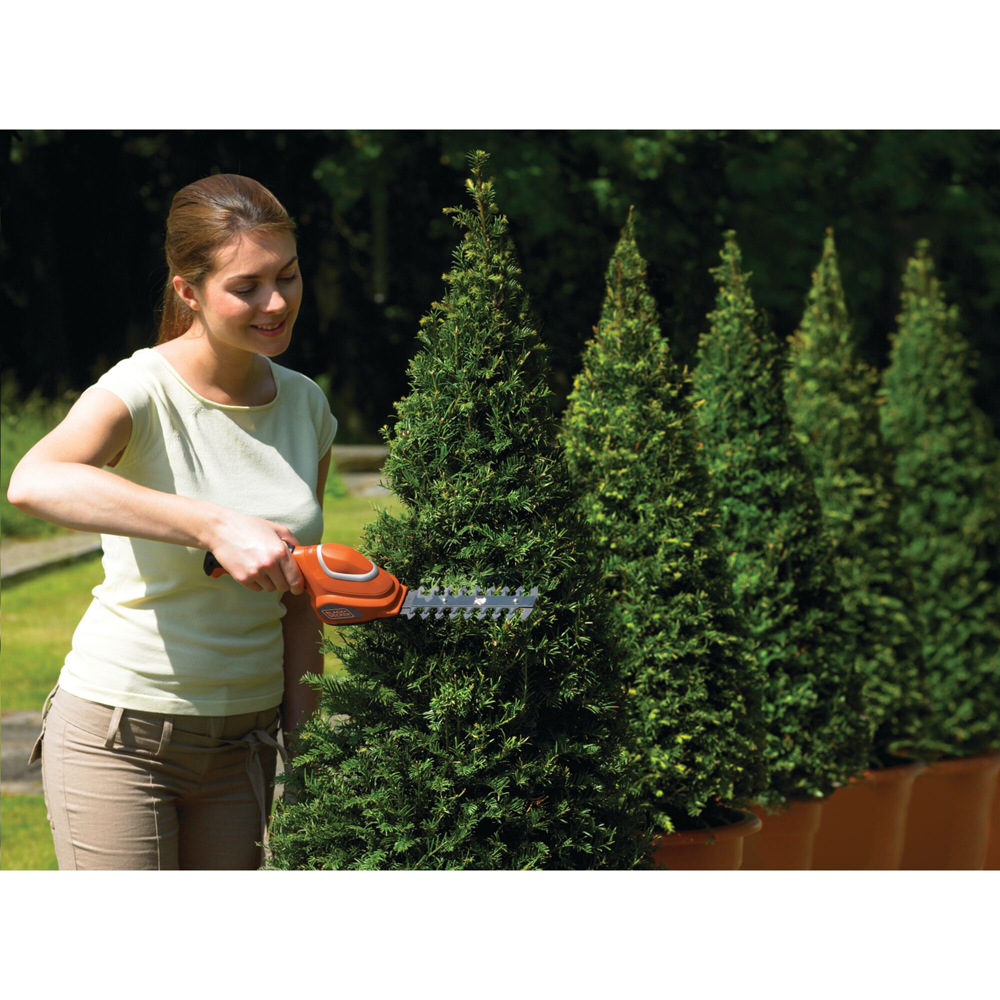 BLACKDECKER GSL700 cordless shrub shear being used to trim potted topiary outdoors.