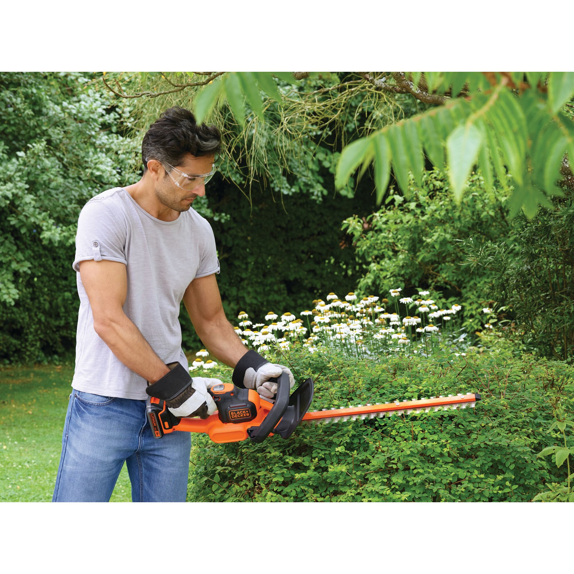 Photo of BLACKDECKER GTC18502PC hedge trimmer in use trimming bushes in a garden.