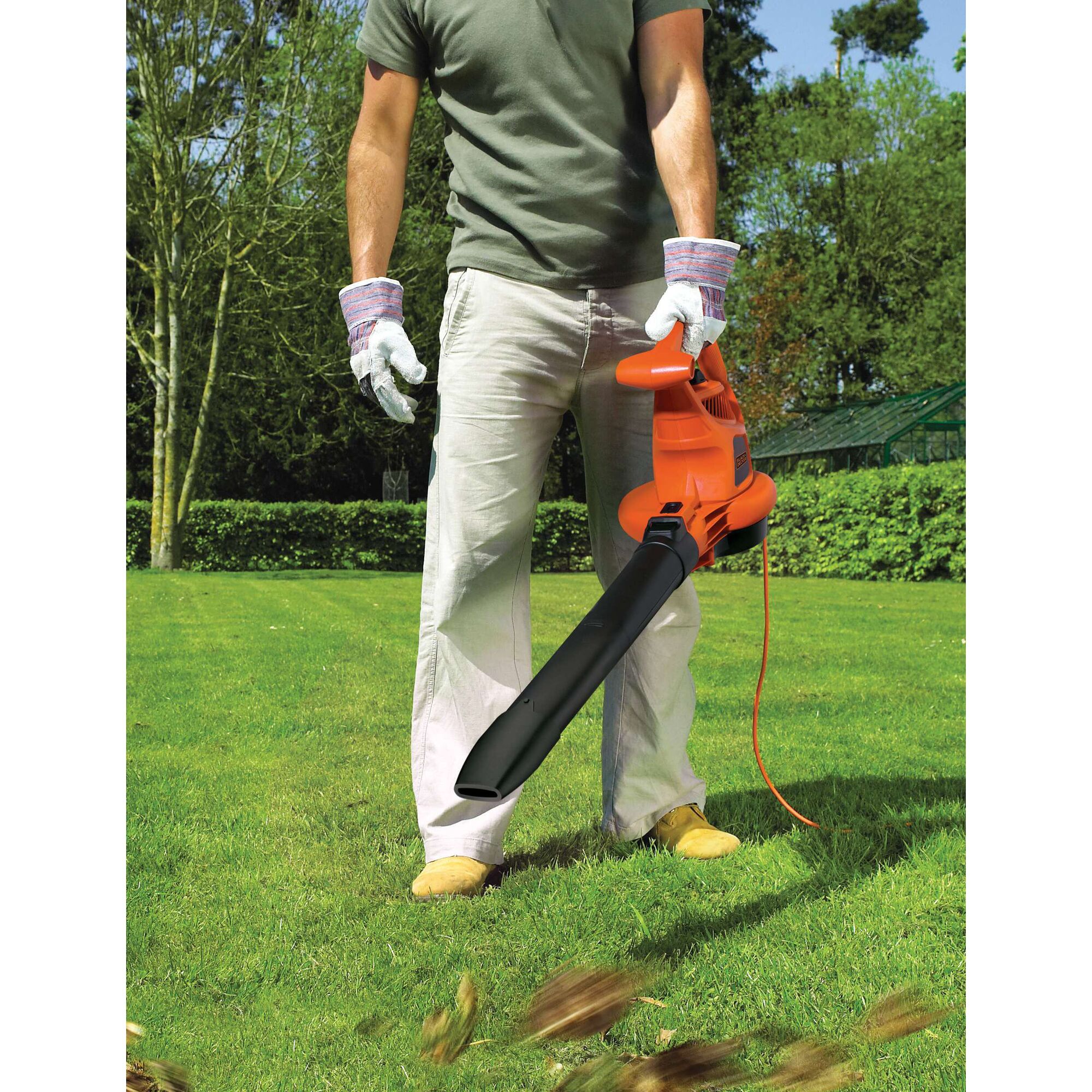 BLACKDECKER GW3030 electric leaf blower in use on grass, person wearing gloves and holding the orange tool.