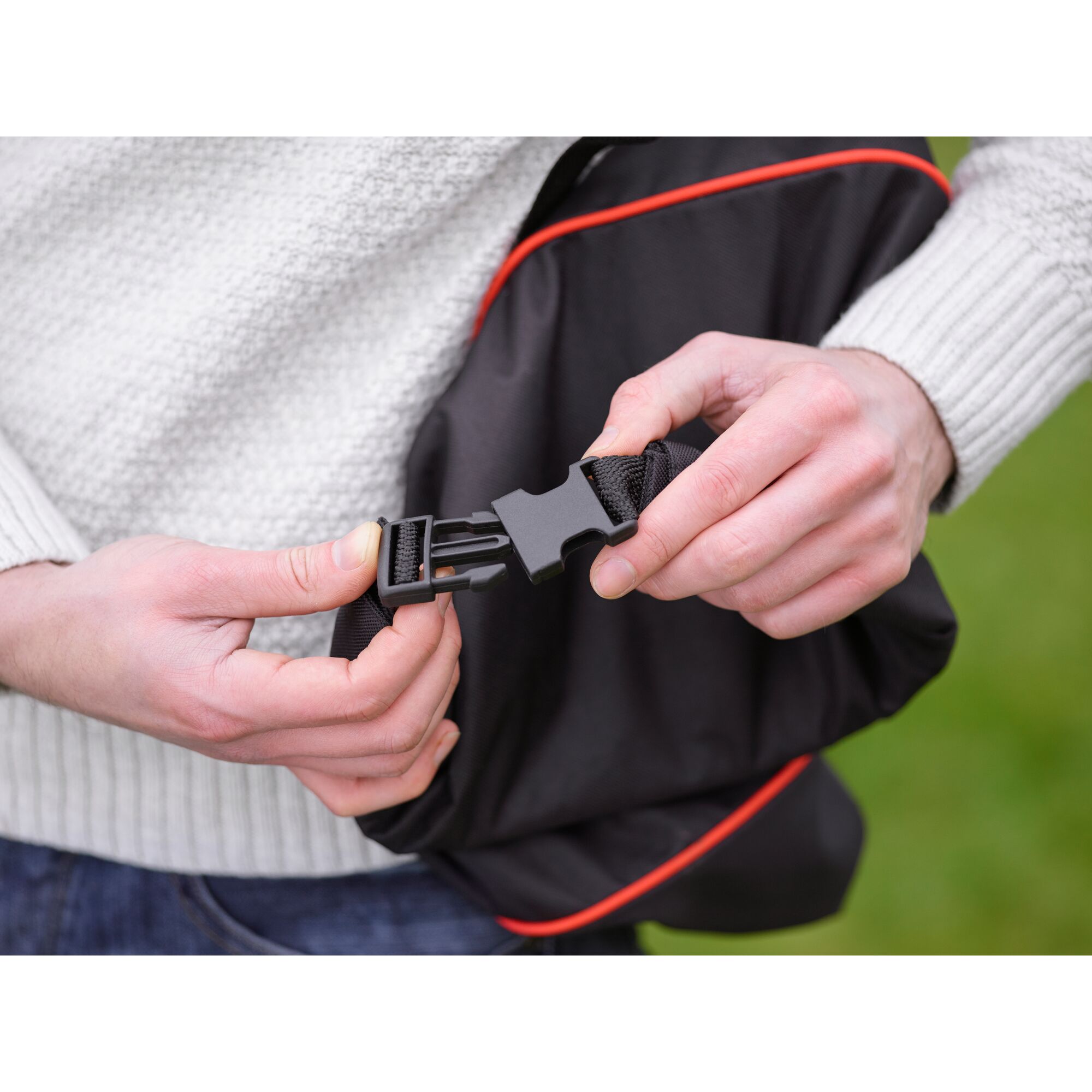 BLACKDECKER GW3031BP photography of hands fastening black buckle on black bag with red trim.