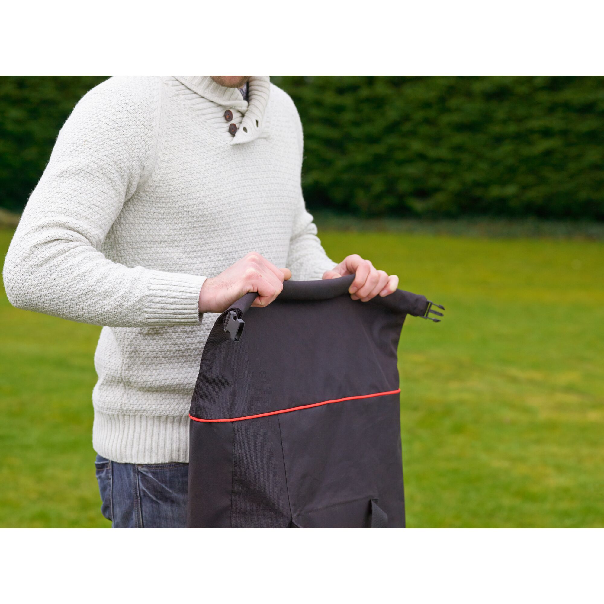 Photo of BLACKDECKER GW3031BP lawn vacuum bag with red trim, held outdoors by a person in a white sweater.