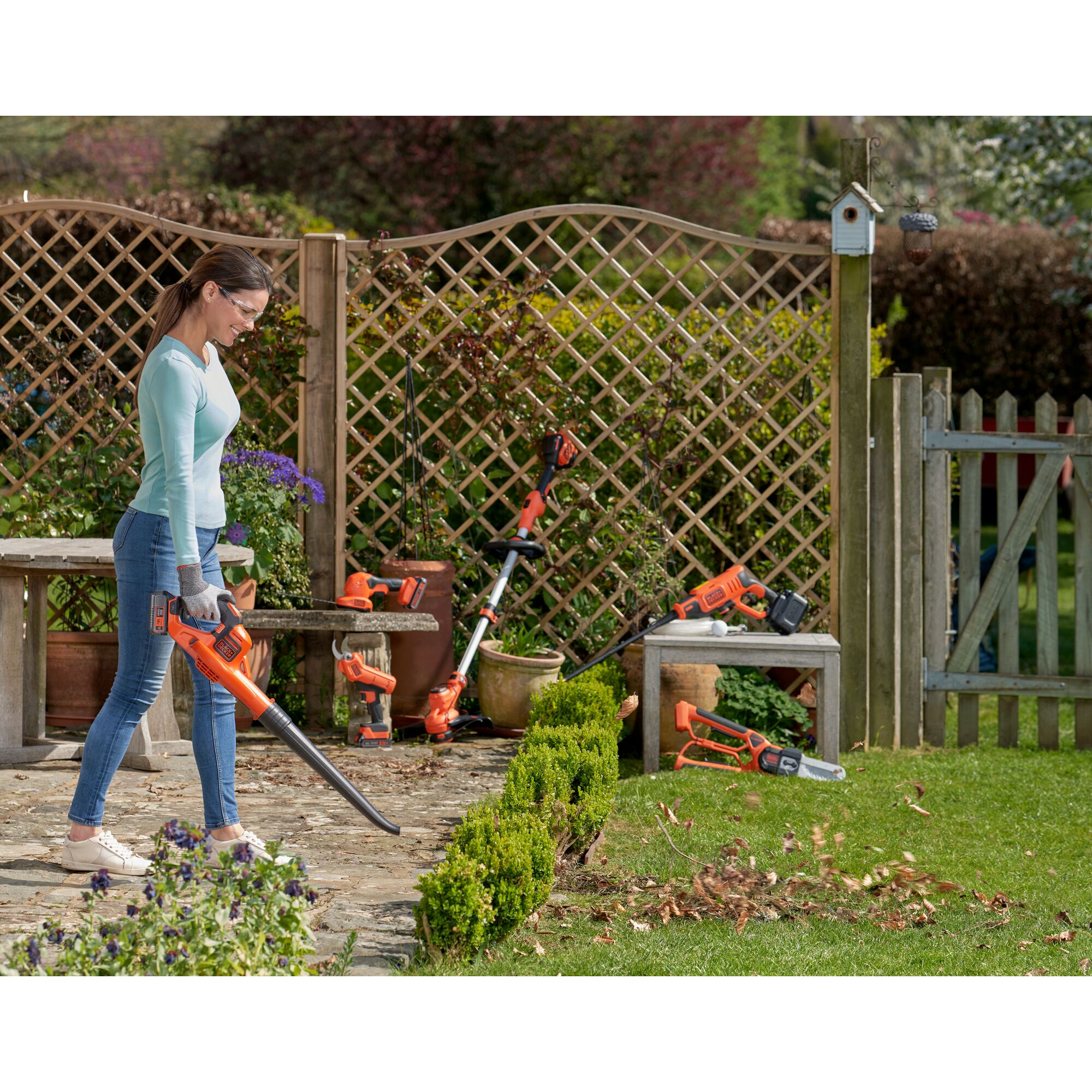 Photo of BLACKDECKER GWC1820PC leaf blower in use on garden path, with other garden tools visible in background.
