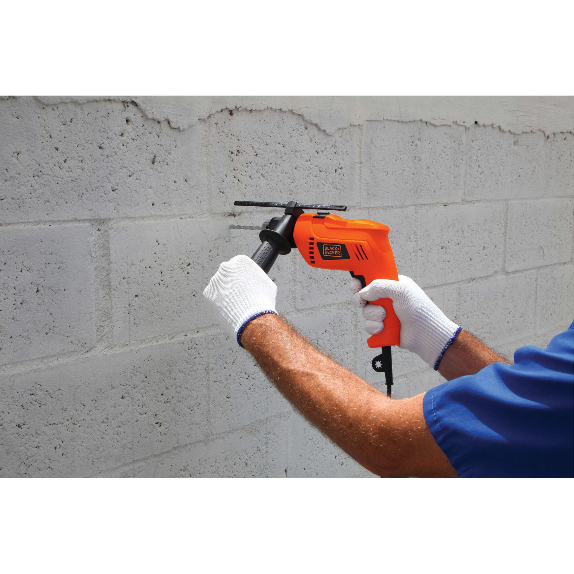 Photography of BLACKDECKER HD650 orange electric drill used on a concrete wall by a person wearing gloves.