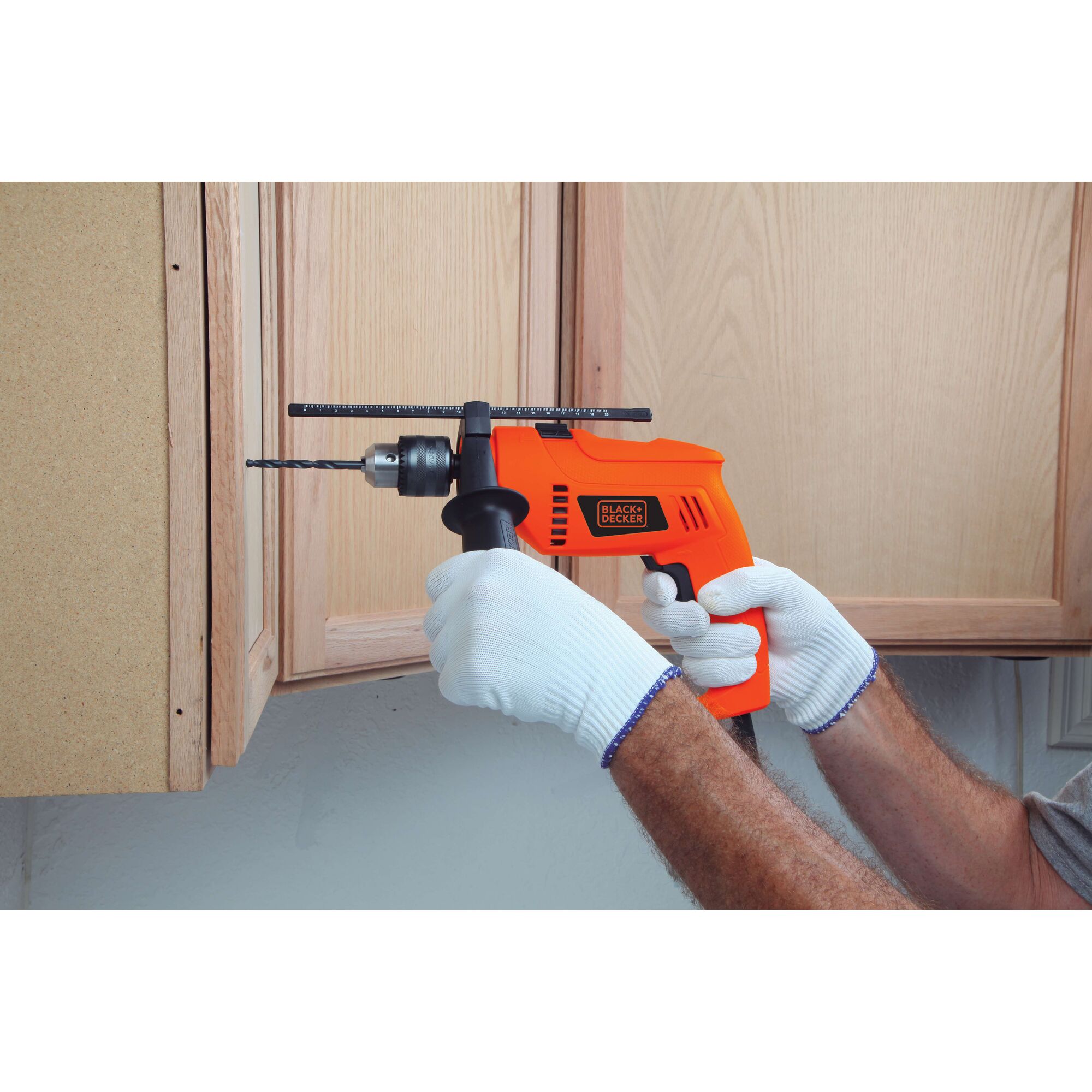 Photo of BLACKDECKER HD650 orange corded drill in use drilling into wooden cabinet, gloved hands holding.