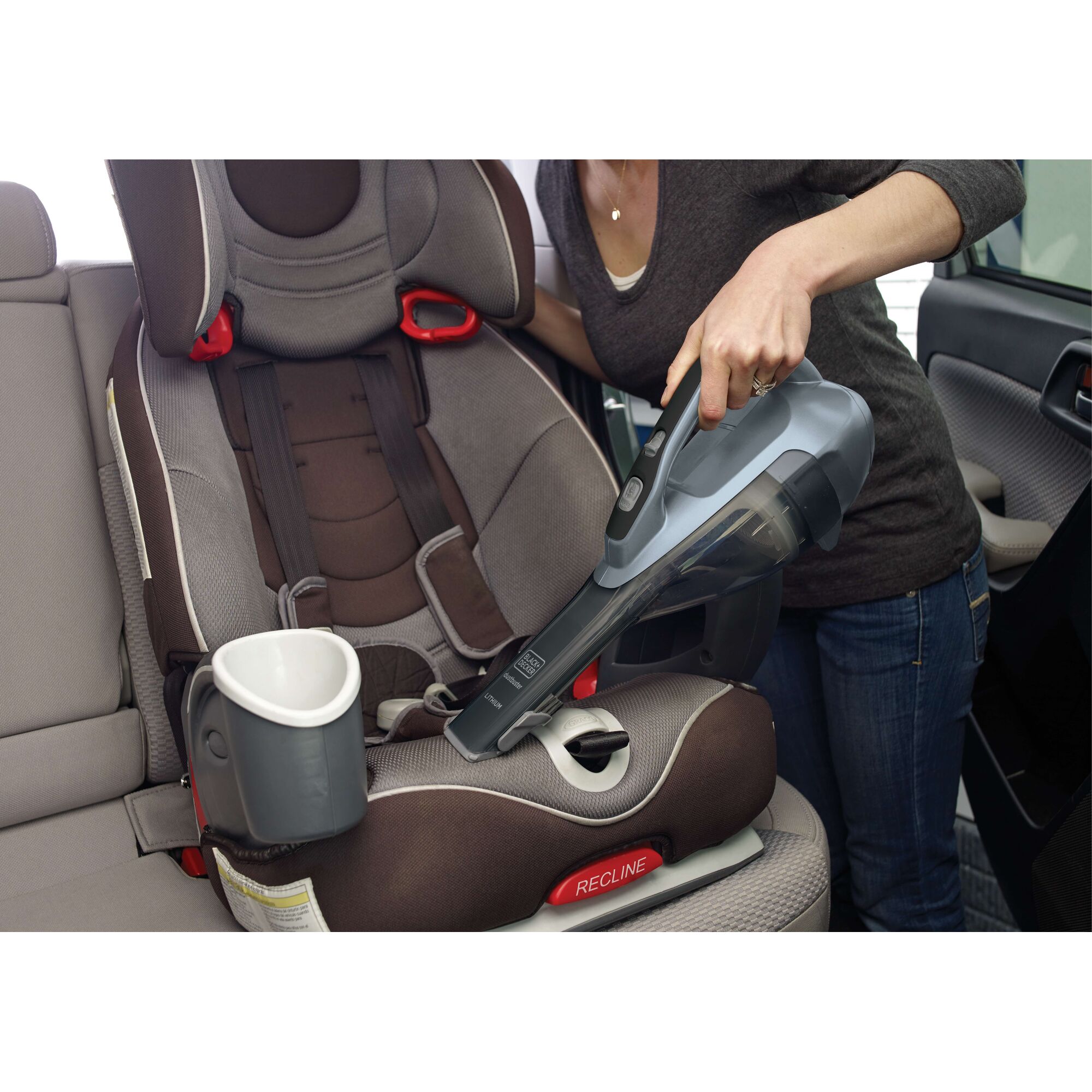 BLACKDECKER HLVA315J32 handheld vacuum cleaning a child car seat in a vehicle, side angle.