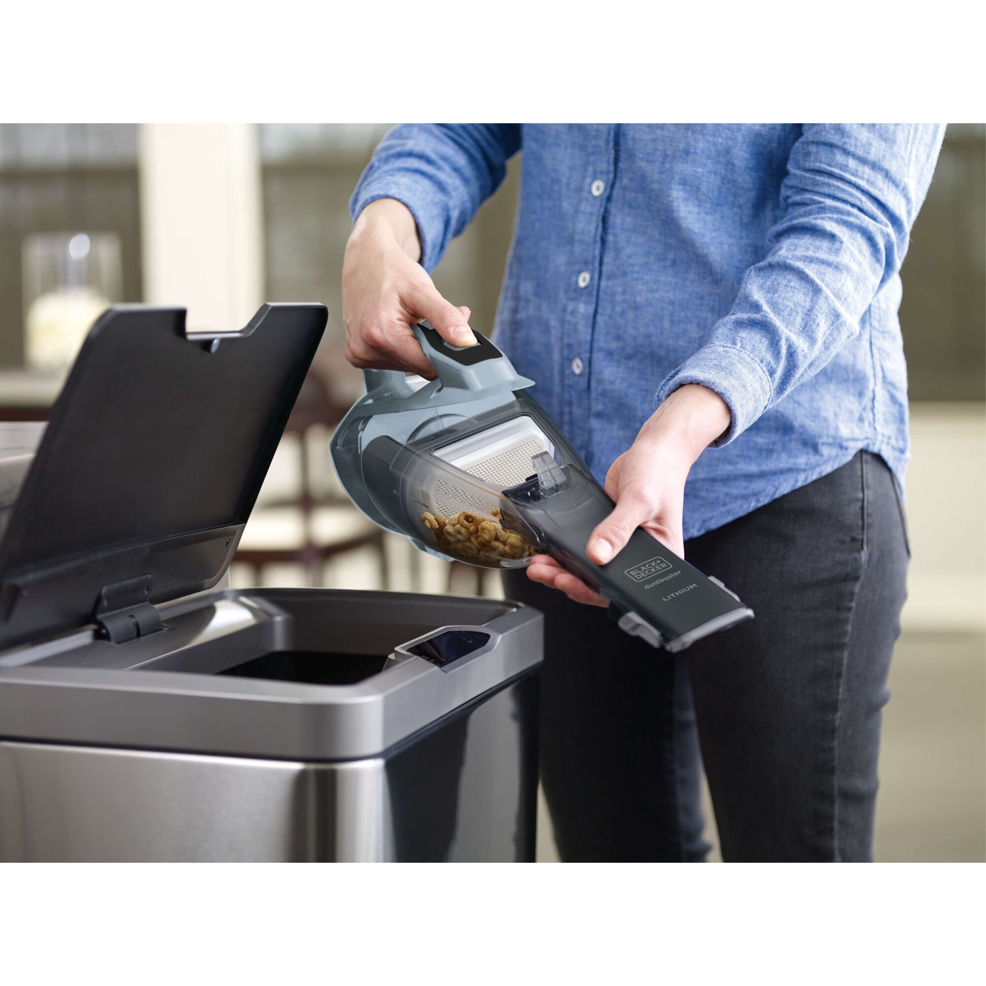 BLACKDECKER HLVA315J32 handheld vacuum being emptied into a trash bin, user holding device.