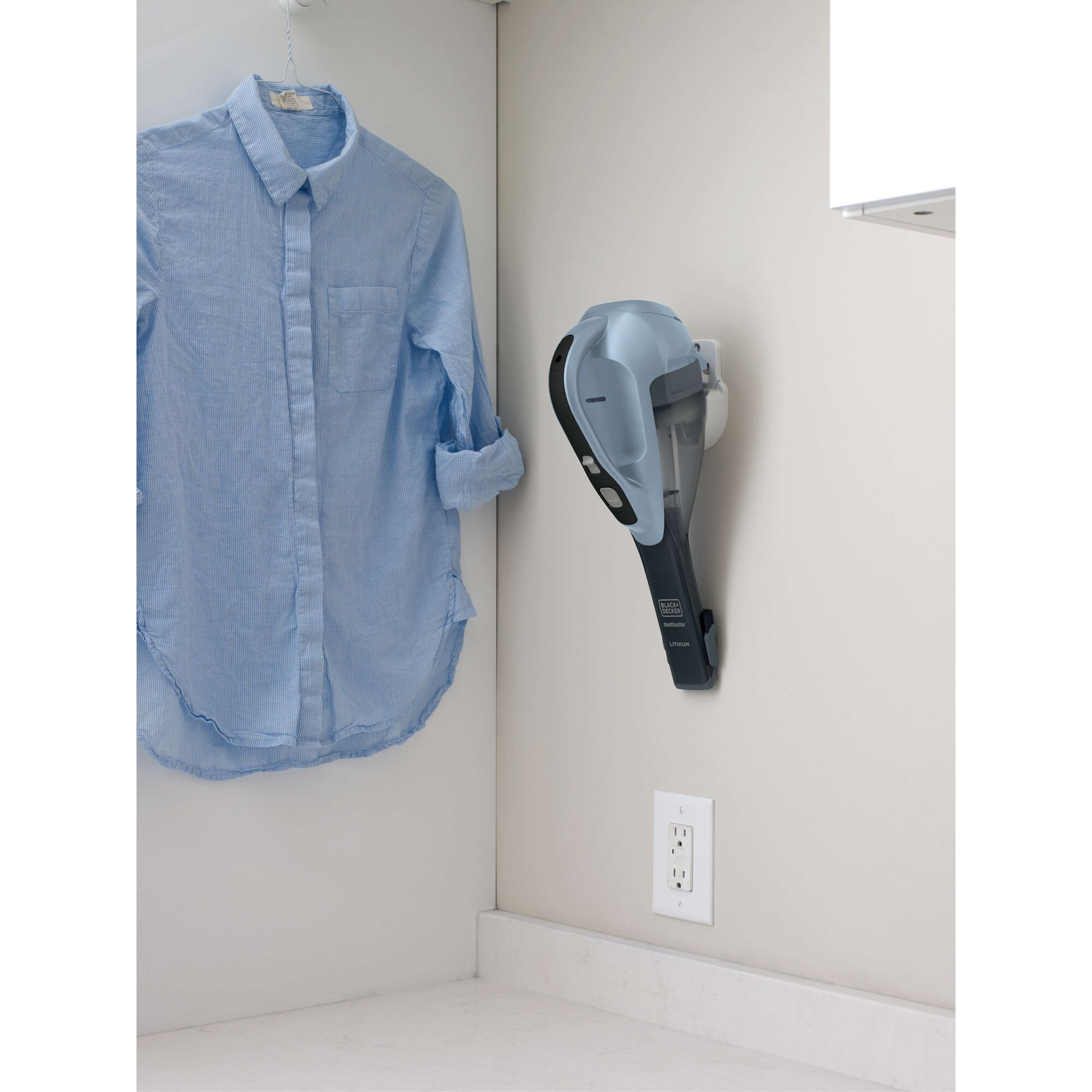 BLACKDECKER HLVA315J32 handheld vacuum in gray mounted on a wall in a laundry room next to a blue shirt.