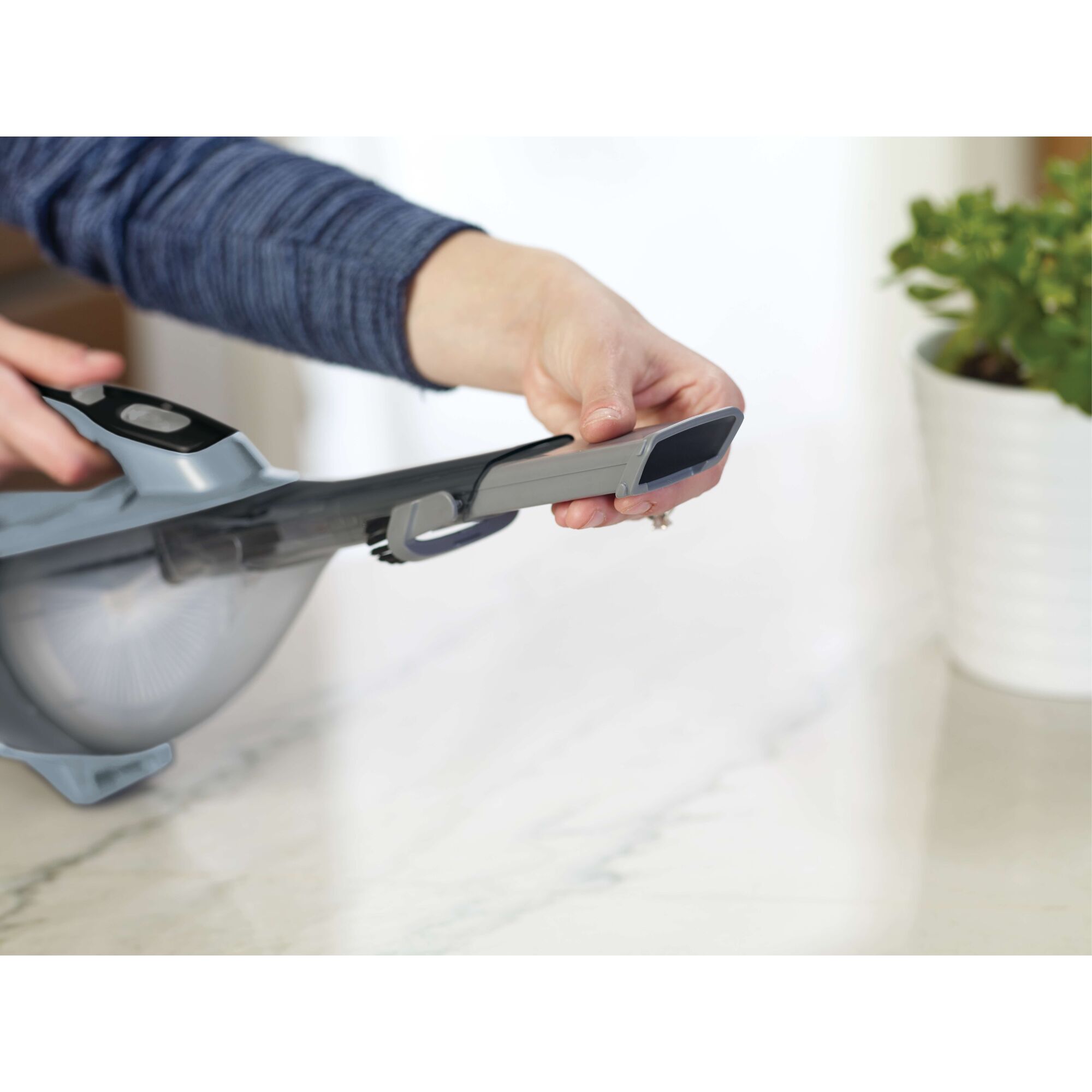 Photo of BLACKDECKER HLVA315J32 handheld vacuum with extension nozzle in use on a countertop.