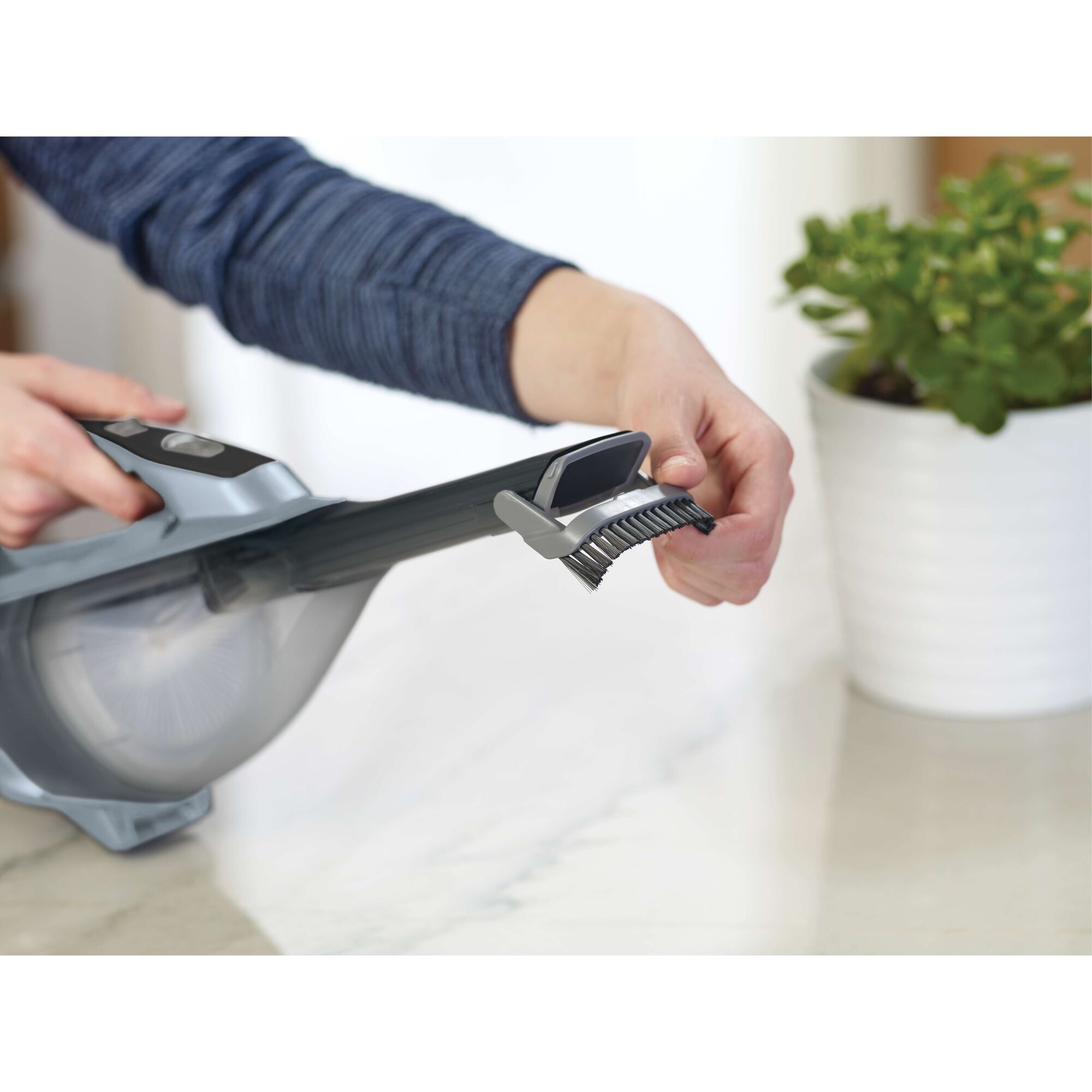 BLACKDECKER HLVA315J32 handheld vacuum with brush attachment in use on a countertop.