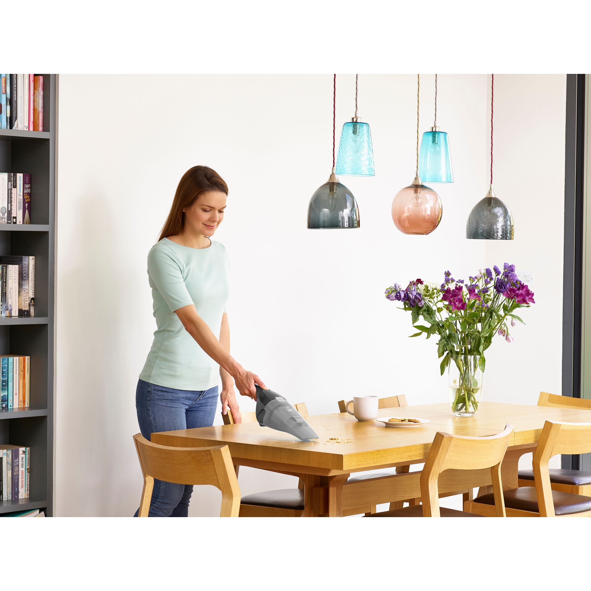 BLACKDECKER HNVC215WBK handheld vacuum cleaning crumbs from dining table in bright modern kitchen.