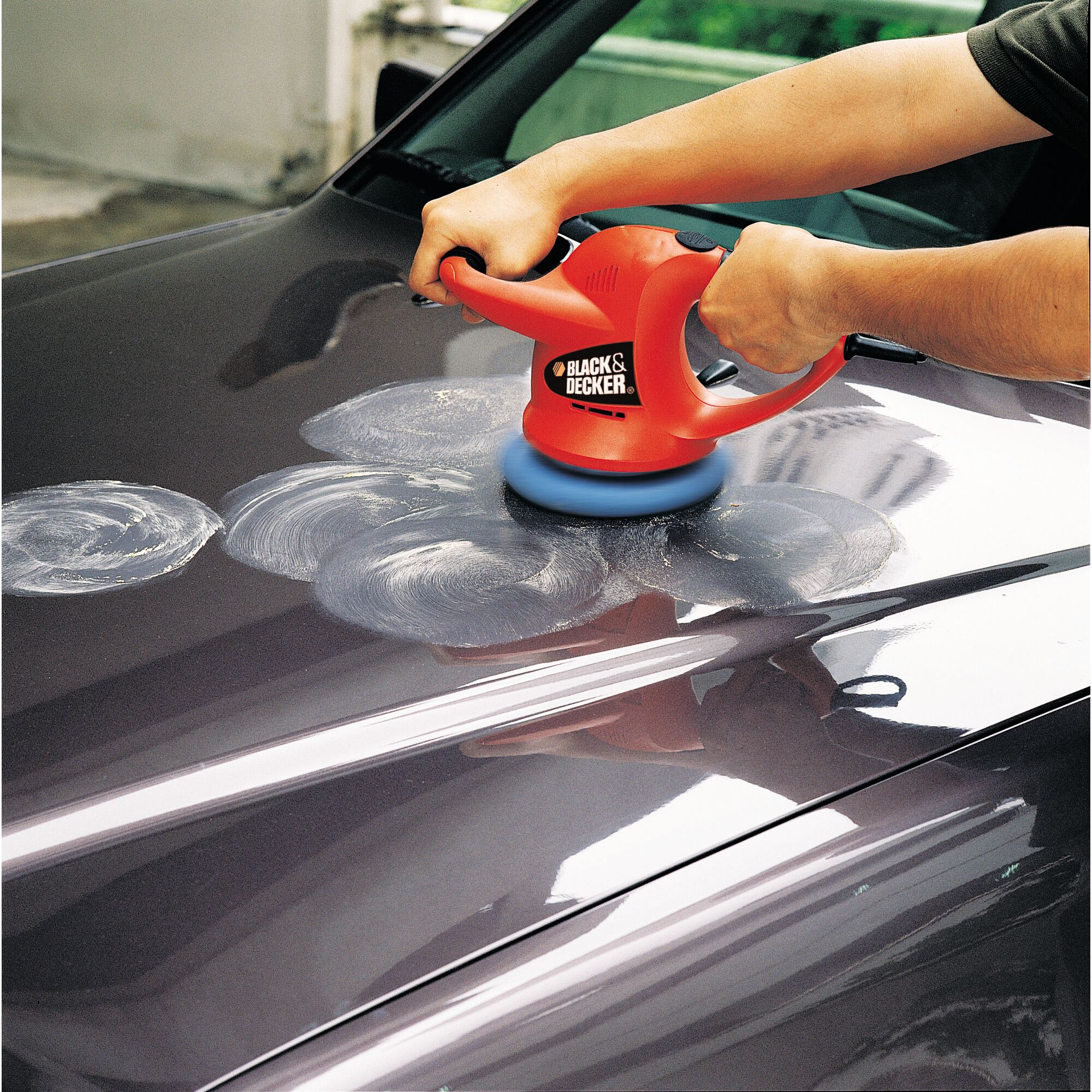 BLACKDECKER KP600 red car polisher in use on a dark vehicle surface, showing circular polishing marks.