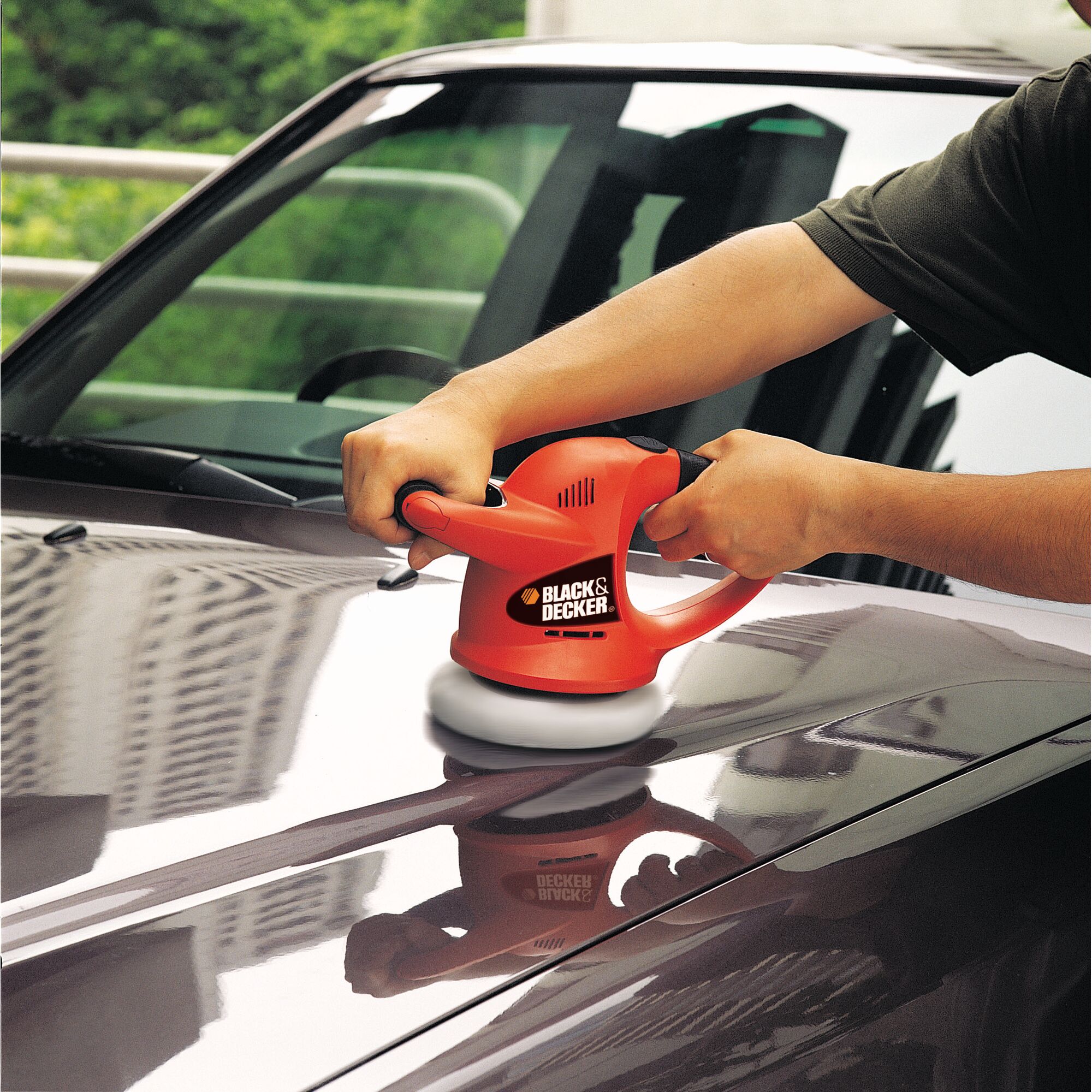BLACKDECKER KP600 car polisher used on vehicle hood, red and black design, handheld tool.