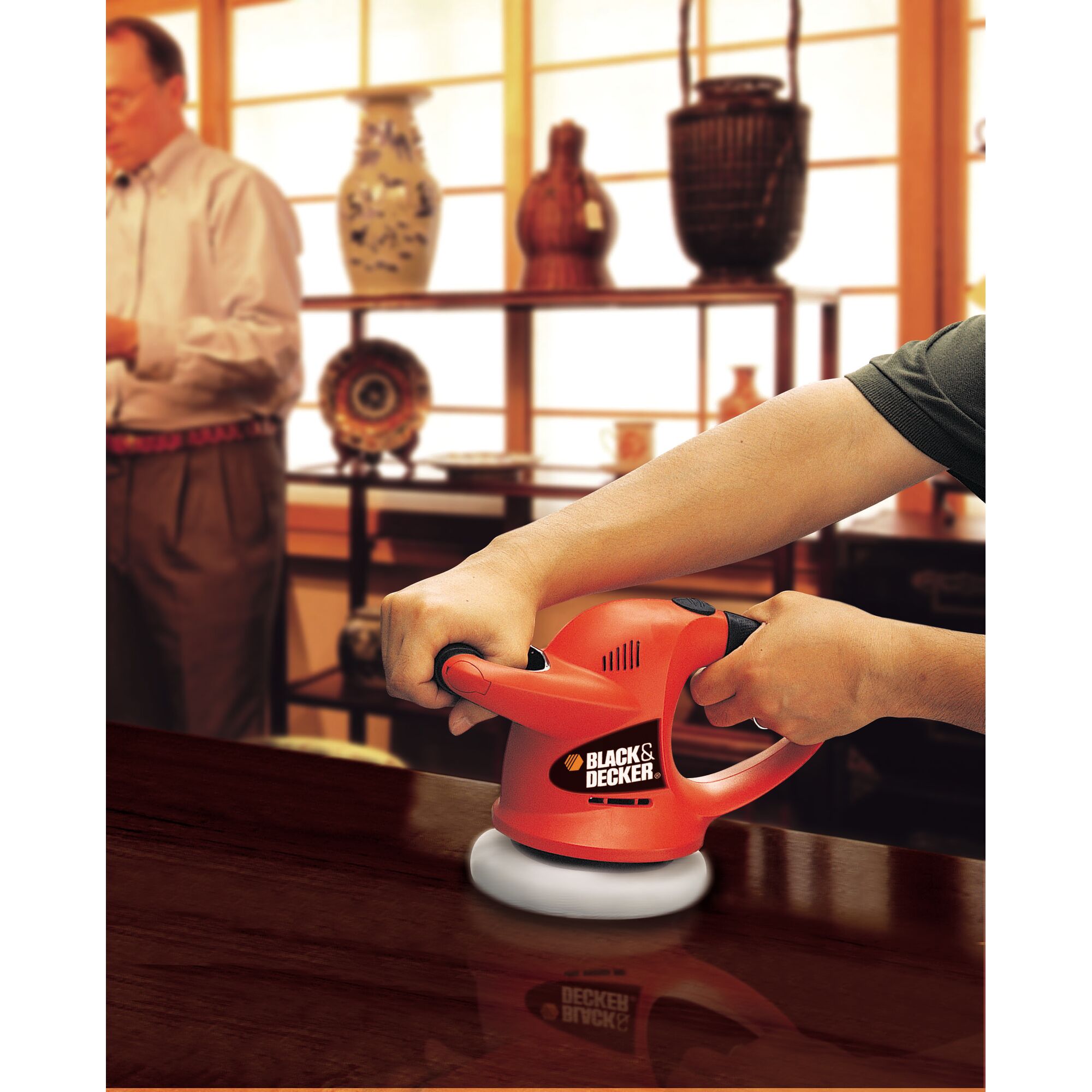 BLACKDECKER KP600 hand-held polisher used on wooden table, with home decor items in background.